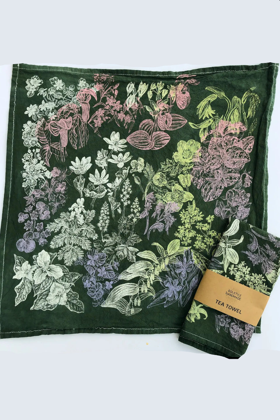 Green tea towel with floral pattern and brand label on a white background ©Solstice Handmade