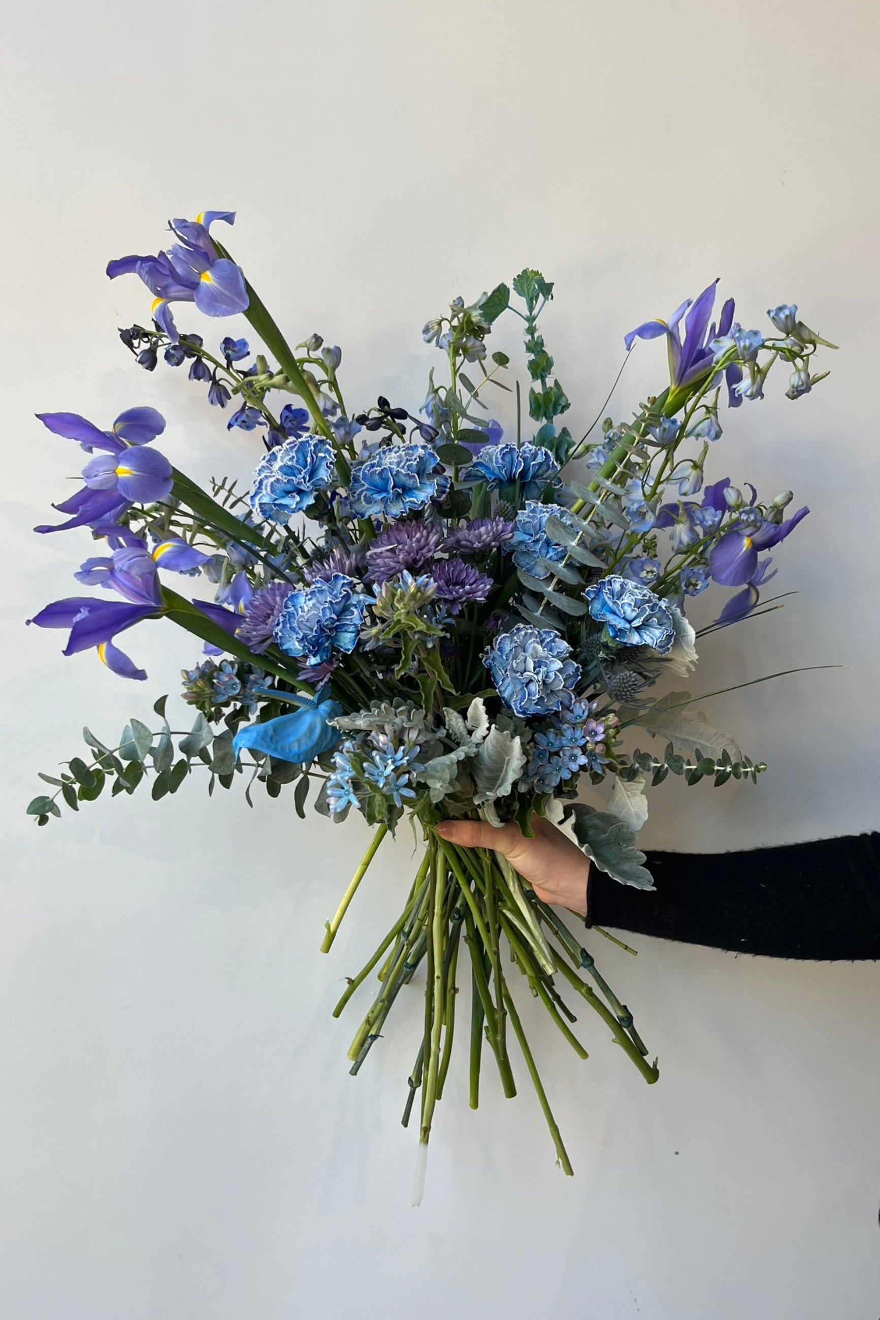 handheld custom arrangement by Sprout Home in shades of blue. Iris, blue carnations and blue anthurium ©Spout Home #size_$200