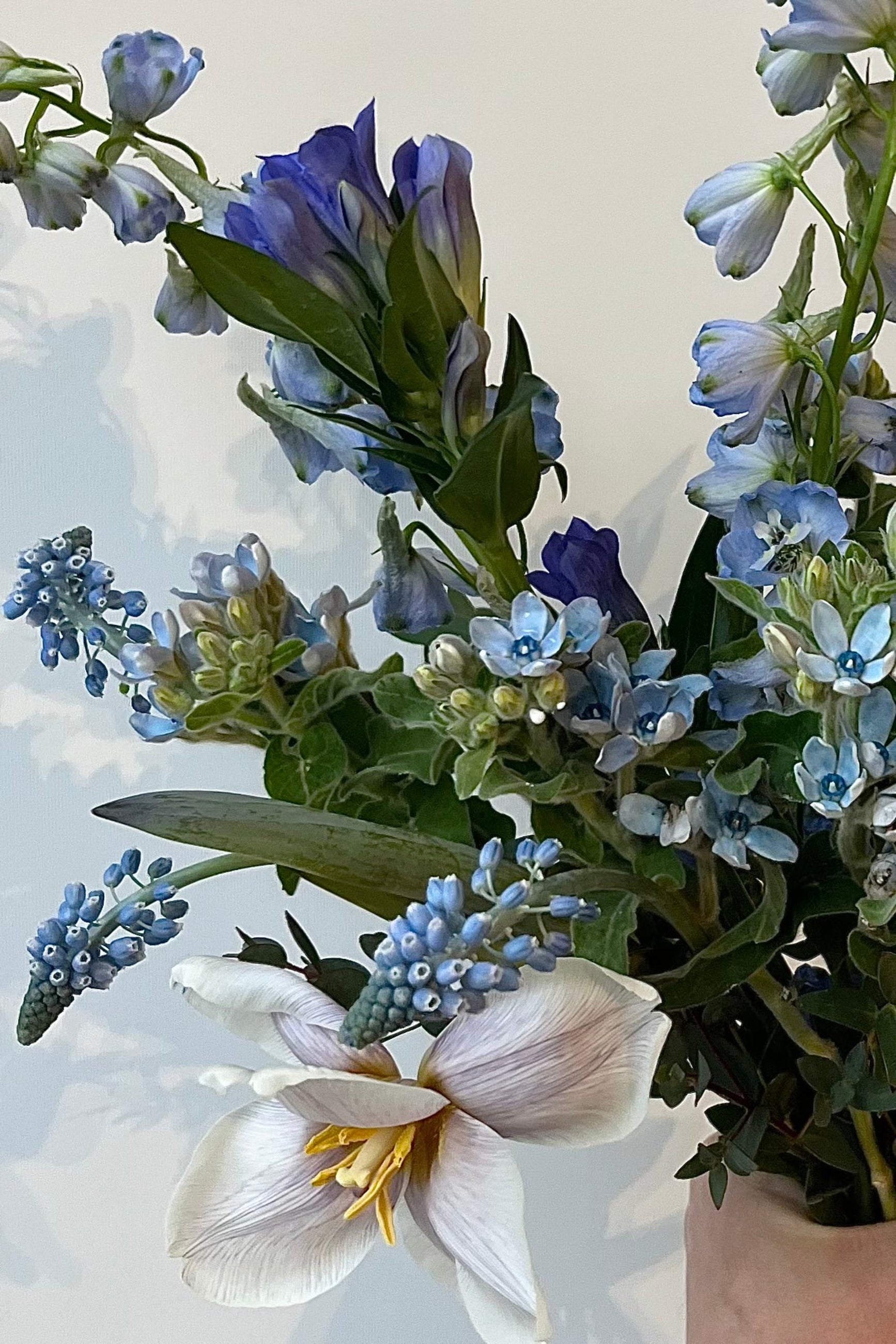 Photo of floral arrangement on a white surface in front of a white wall at Sprout Home. The flowers are various shades of blue, indigo, aqua and teal. ©Sprout Home #size_PLP