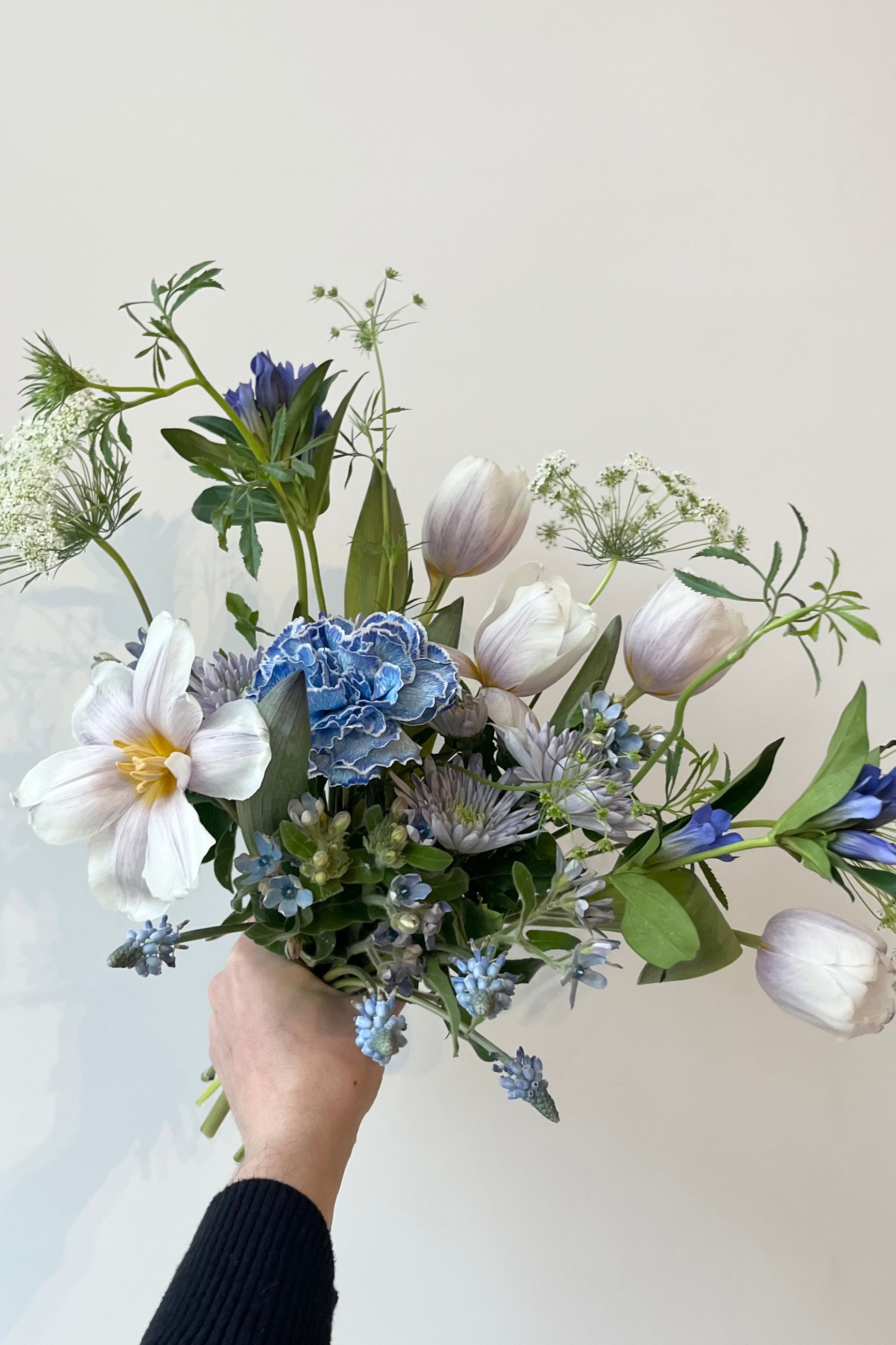 Photo of floral arrangement on a white surface in front of a white wall at Sprout Home. The flowers are various shades of blue, indigo, aqua and teal. ©Sprout Home #size_$75