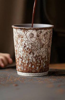 Ceramic cup with intricate floral patterns being filled with coffee. ©Haku