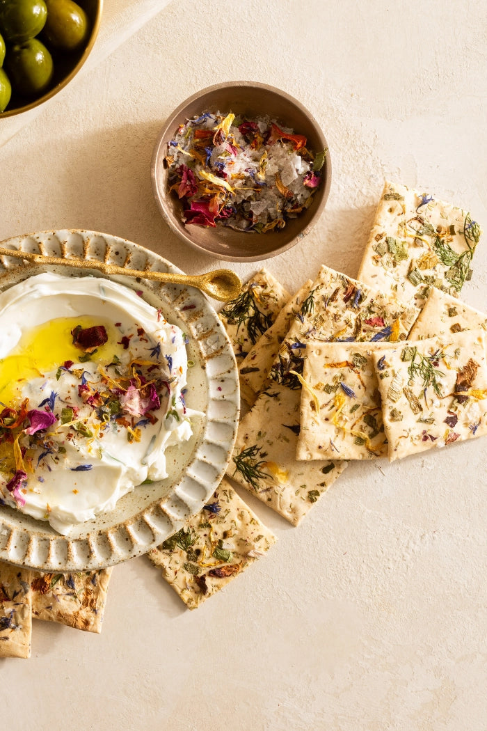 Dessert platter with a bowl of whipped cream, dried flowers, and crackers on a light surface. ©Flouwer Co