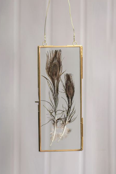 brass hanging frame with feathers inside a on a light gray background ©Vagabond Vintage