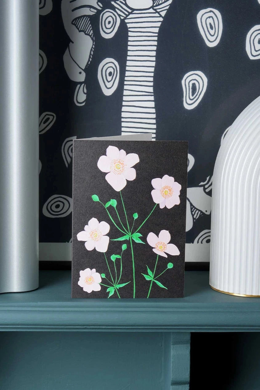 Stengun Drawings Anemone card on a shelf in front of a black and white wallpaper.