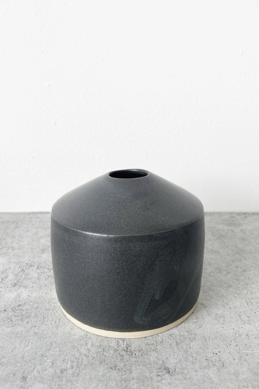 Dark gray Siros ceramic vase on a light gray surface with a white background ©Little Fire Ceramics