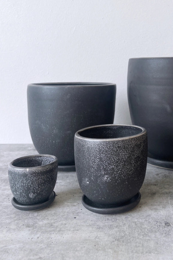 Collection of various sized table top planters in black against a white wall ©Little Fire Ceramics
