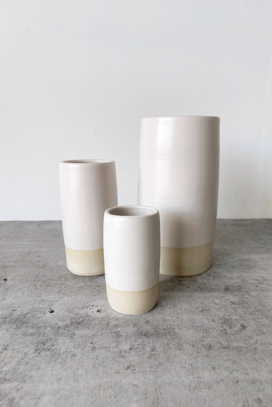 Three ceramic white Jaqueline vases with two-tone design on a gray surface. ©Little Fire Ceramics