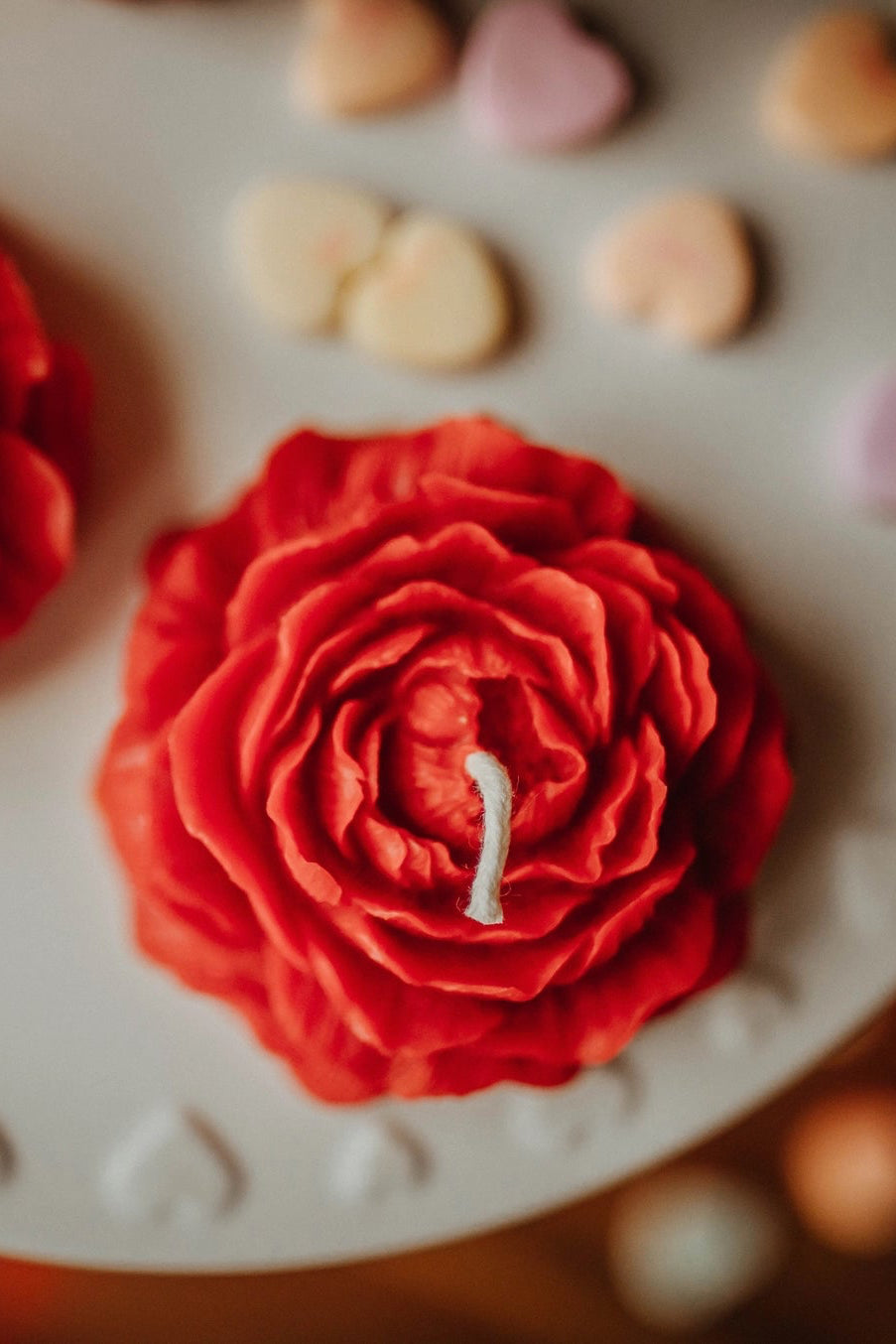 Two red Peony-shaped candles on a white cake with heart-shaped candies. ©The Holten Homestead