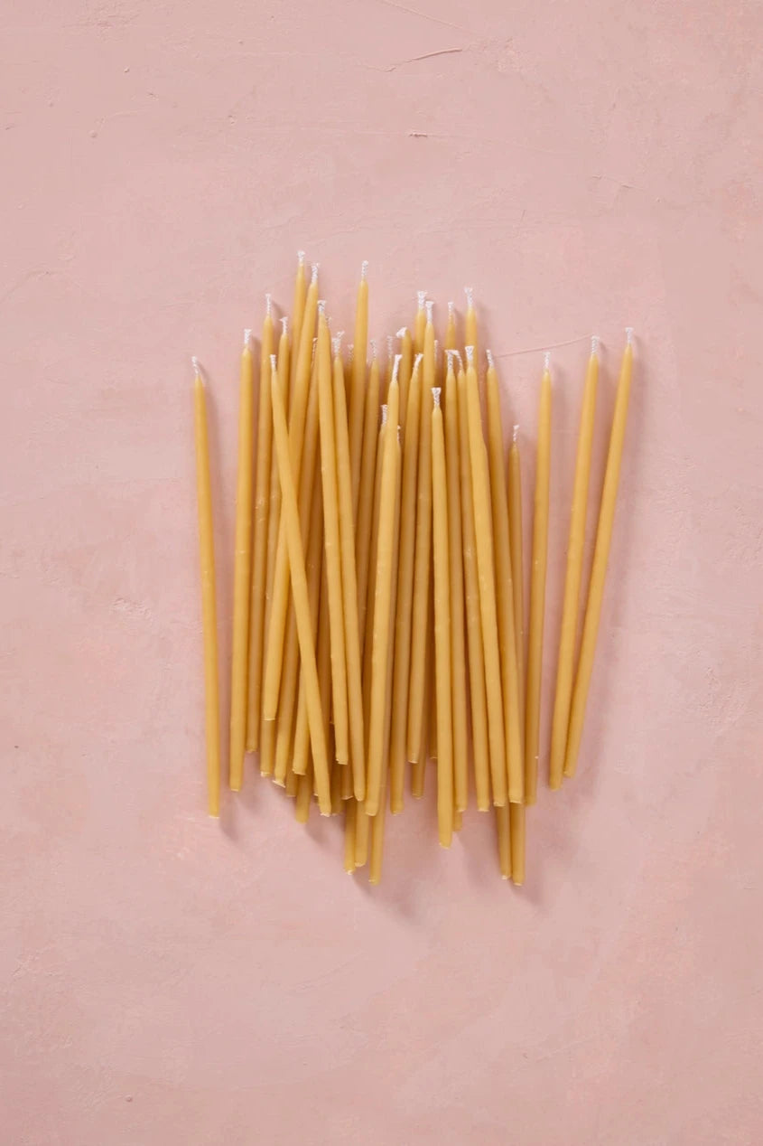 Knot & Bow Tall Natural beeswax candles in a pile