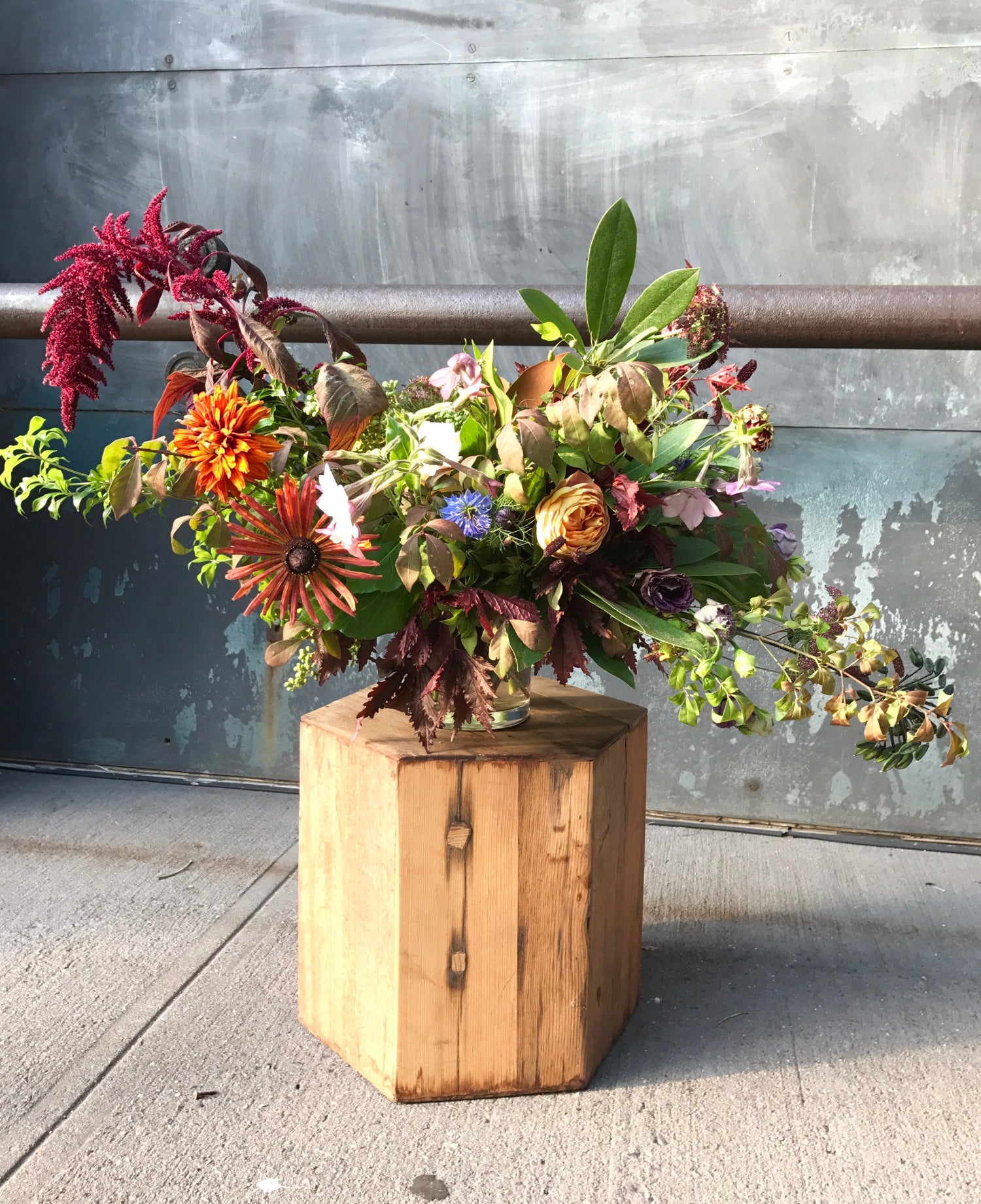 A large Fall season arrangement featuring amaranthus and rudbeckia by SPROUT HOME. sitting on a wood pedestal. Photo by Sprout Home.