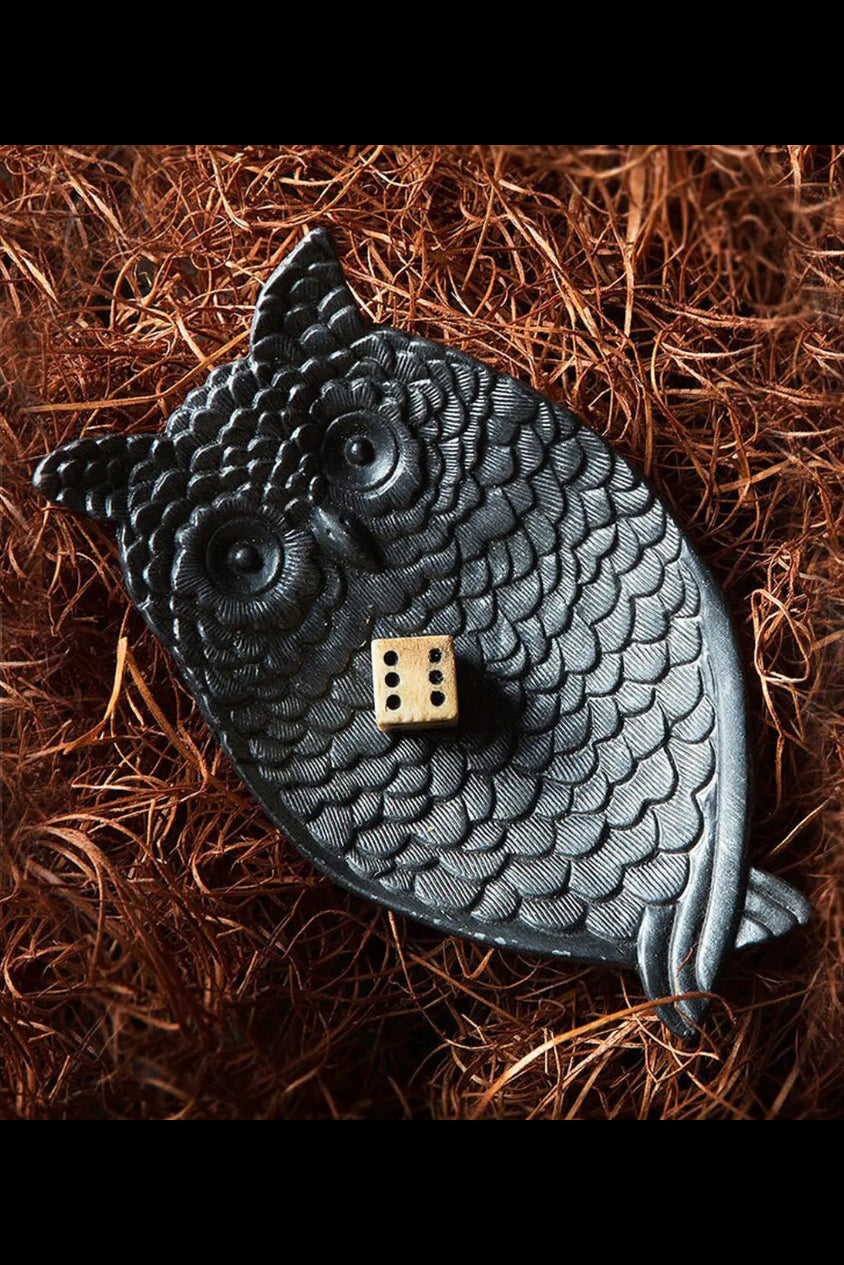 Black owl-shaped object with a small dice on a brown textured background ©Vagabond Vintage