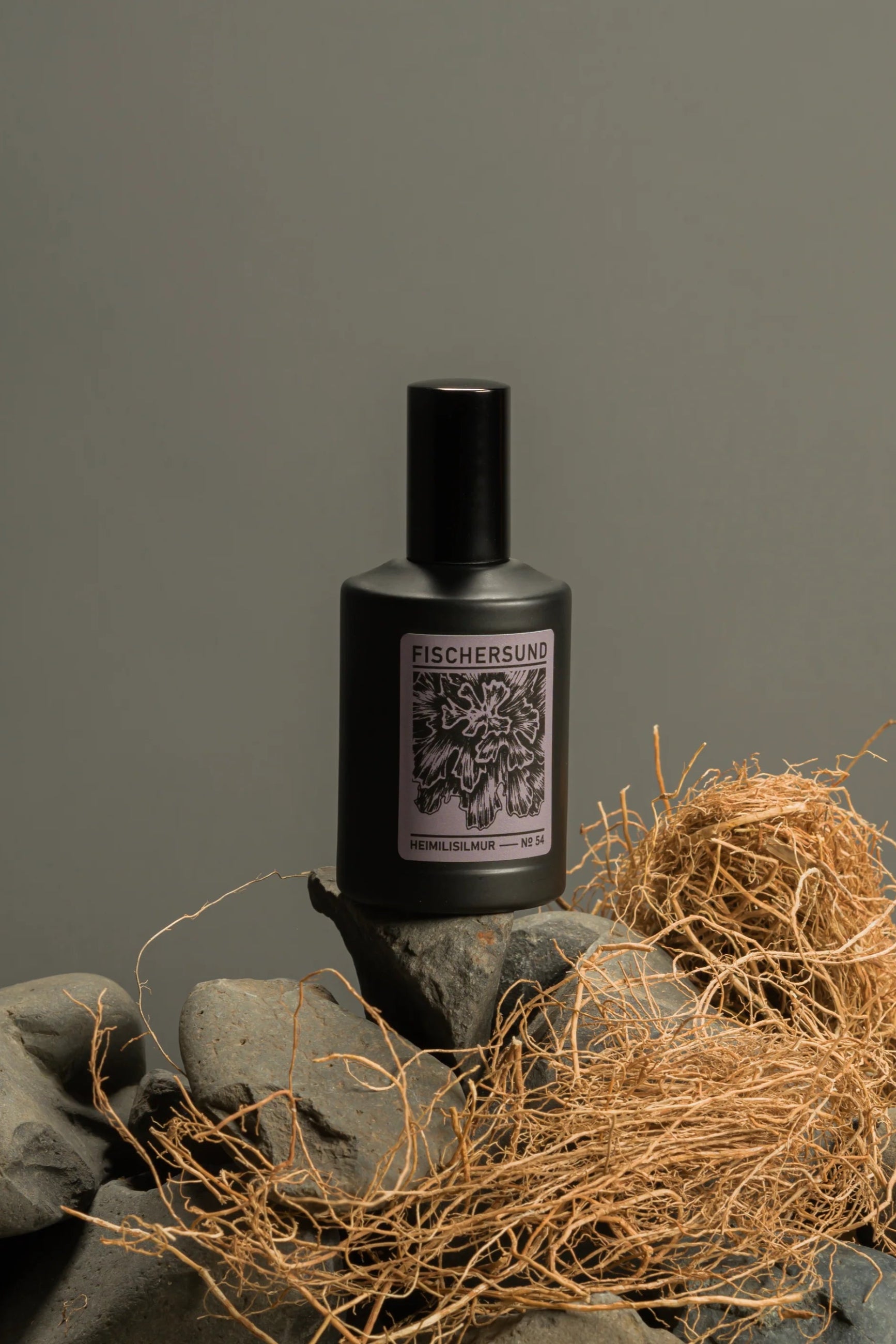 Bottle of Fischers Fischersund Home Spray #54 on a stone surface with hay, against a gray background ©Fischersund