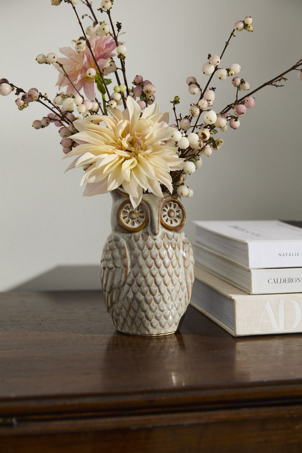 Owl-shaped vase with flowers on a wooden surface next to books ©Accent Decor