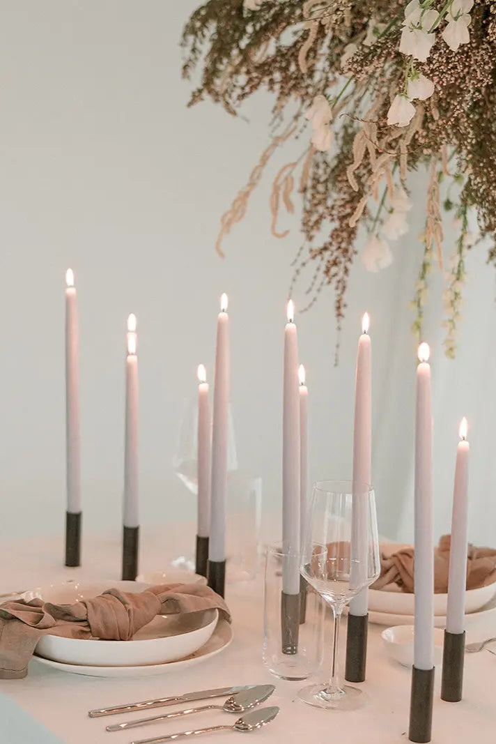 Elegant table setting with candles, plates, and cutlery on a light surface. Bluebell 14" Beeswax Taper Candles by Mo & Co. ©Mo & Co.