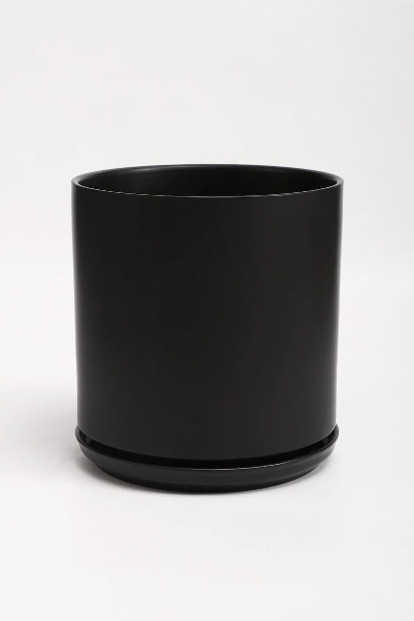 A black planter and saucer in front of a white wall. Shown from the front. ©LBE Design