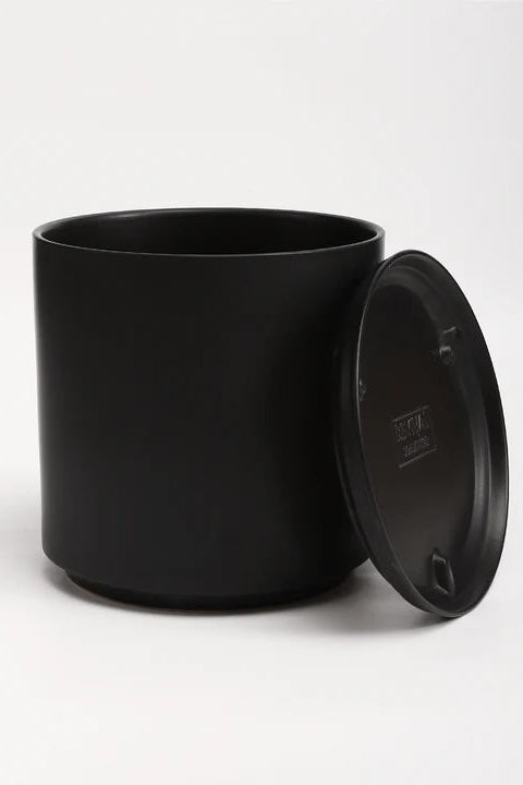 A black planter and saucer in front of a white wall. Shown from the front. ©LBE Design
