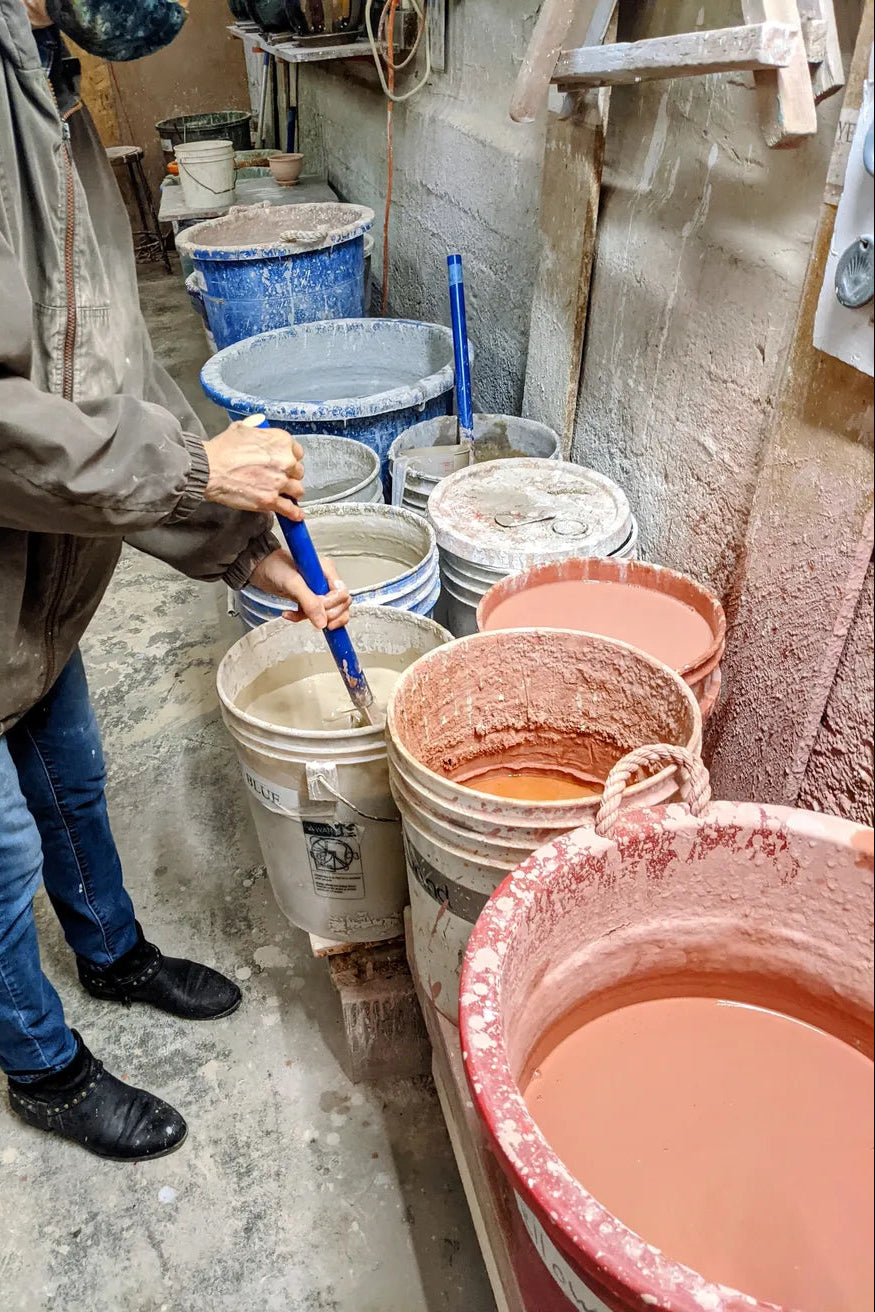 Person working with buckets and containers of glaze colors at Bruning Pottery ©Bruning Pottery