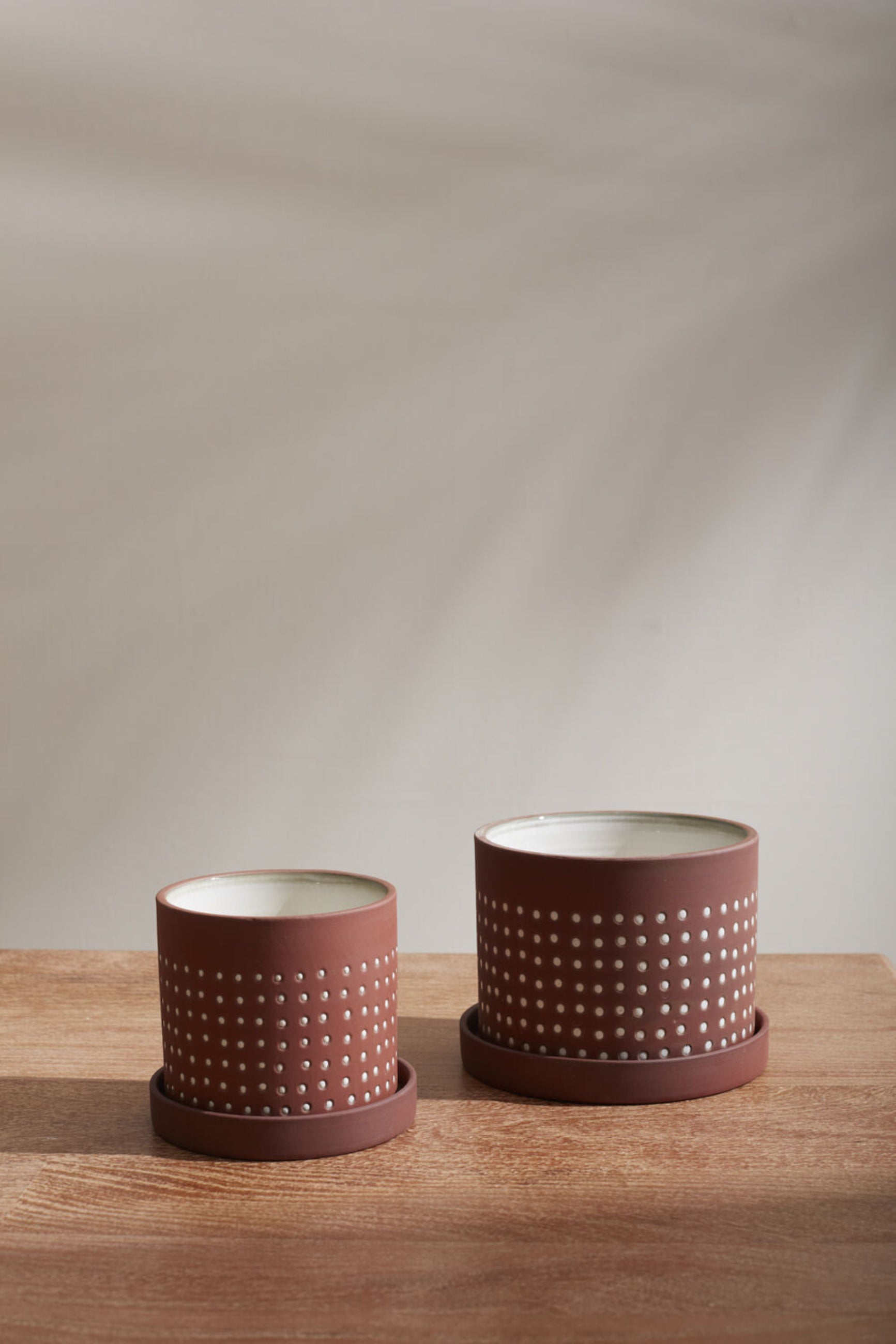 Two sizes of Salamanca pots empty and sitting on a wood table.