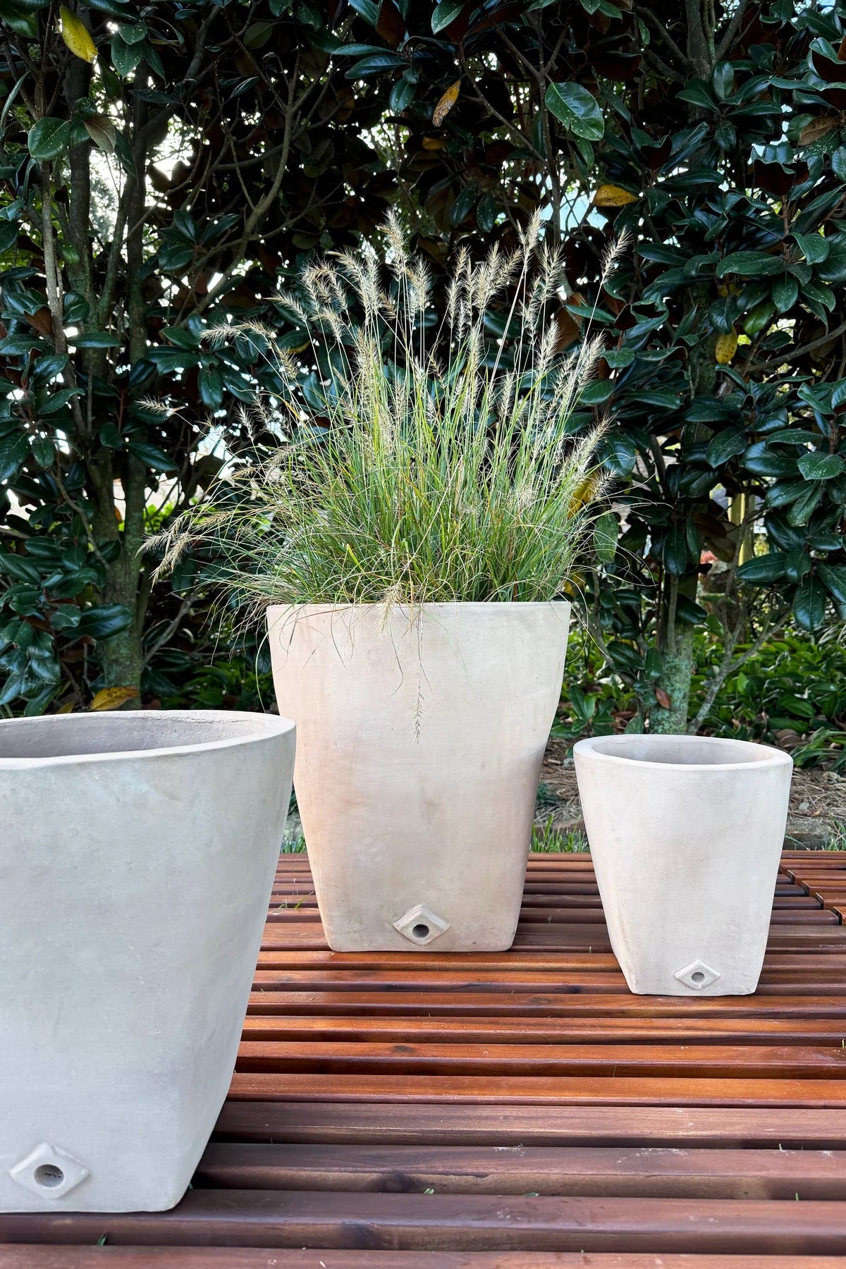 Three large stone Yuki planters with grasses on a wooden deck ©Anamese
