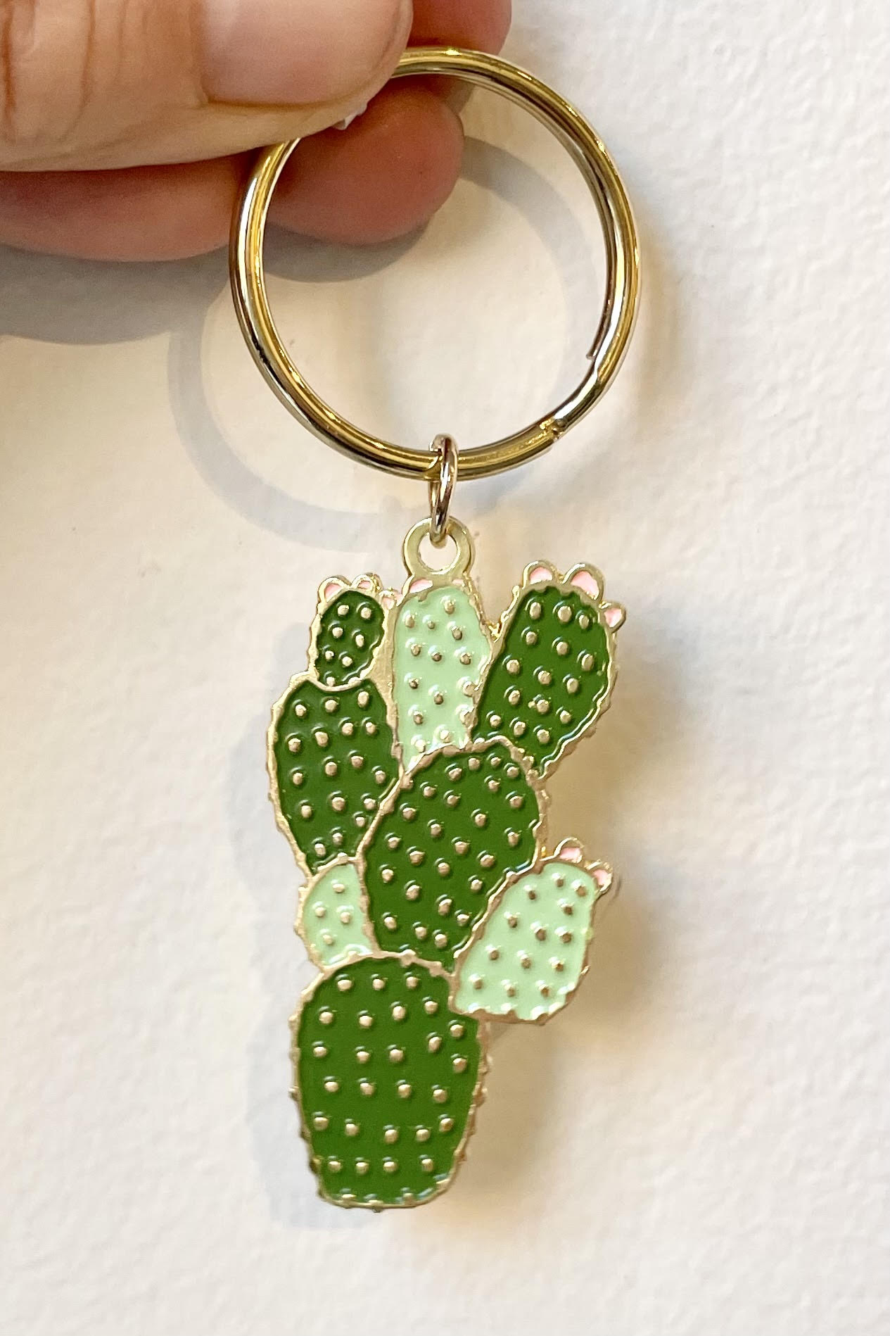A hand holds the Cactus Keychain against a white backdrop.