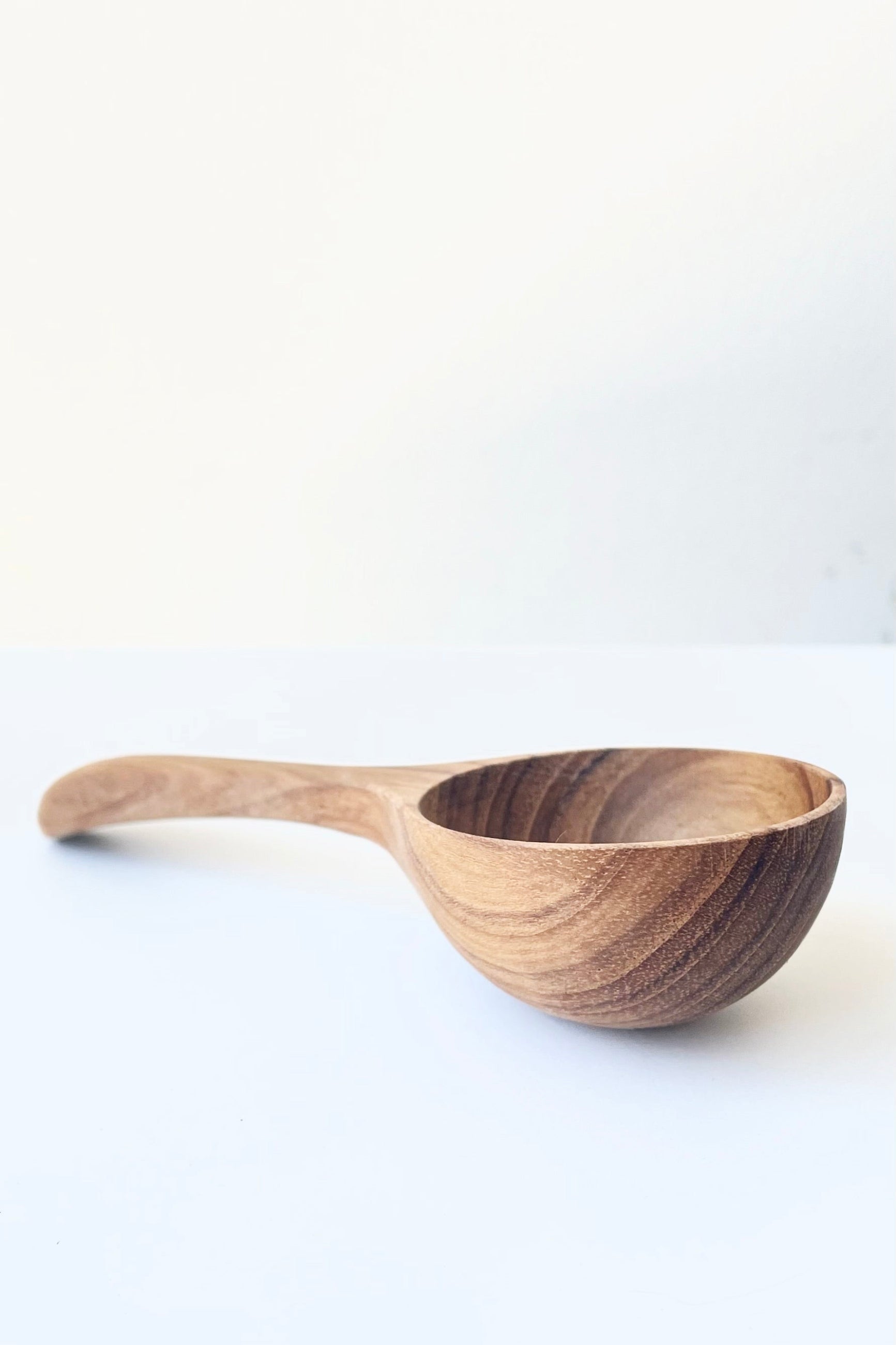 A side view of the handcrafted Teak Scoop against a white backdrop ©Sprout Home
