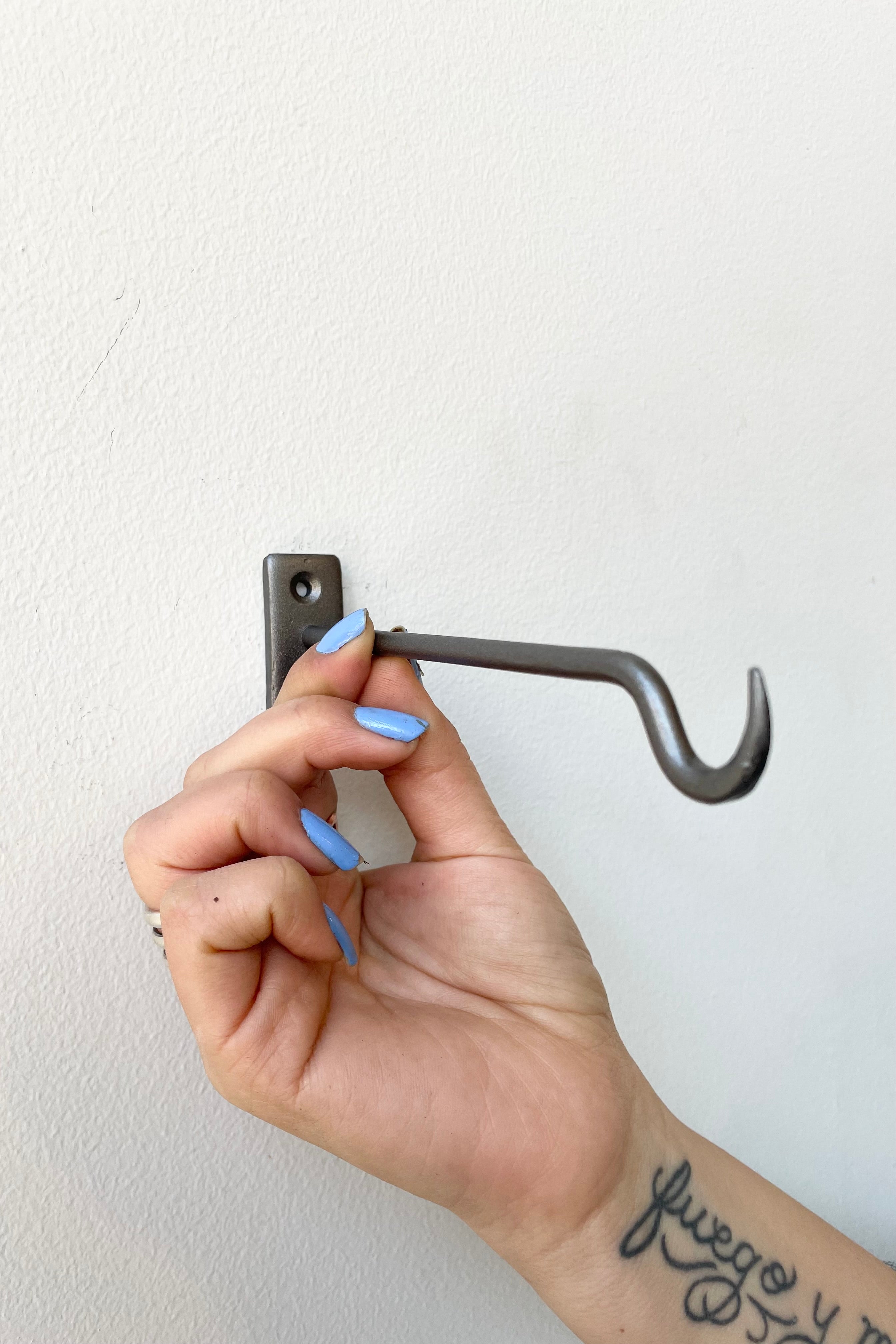 Bijou natural 6" wall hook being held against a white wall at Sprout Home.
