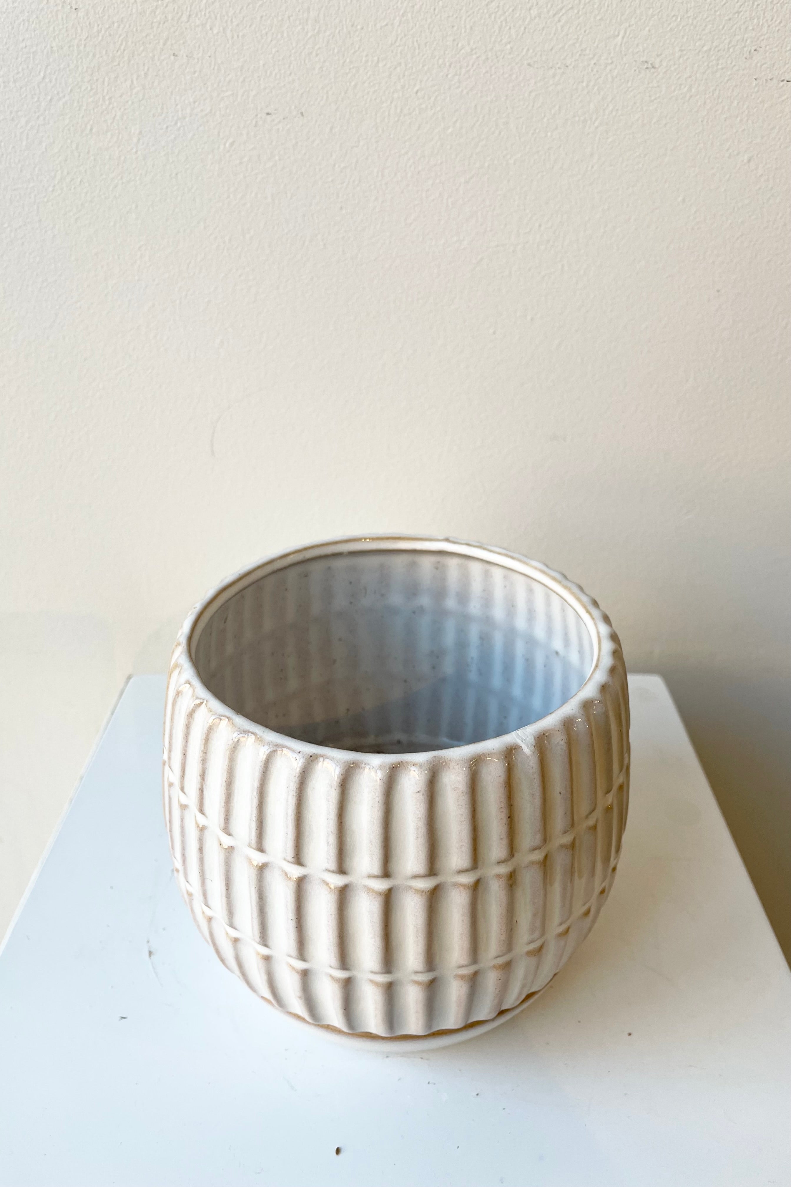 The stoneware Ramos 4" pot with drain hole and saucer against a white wall at Sprout Home.