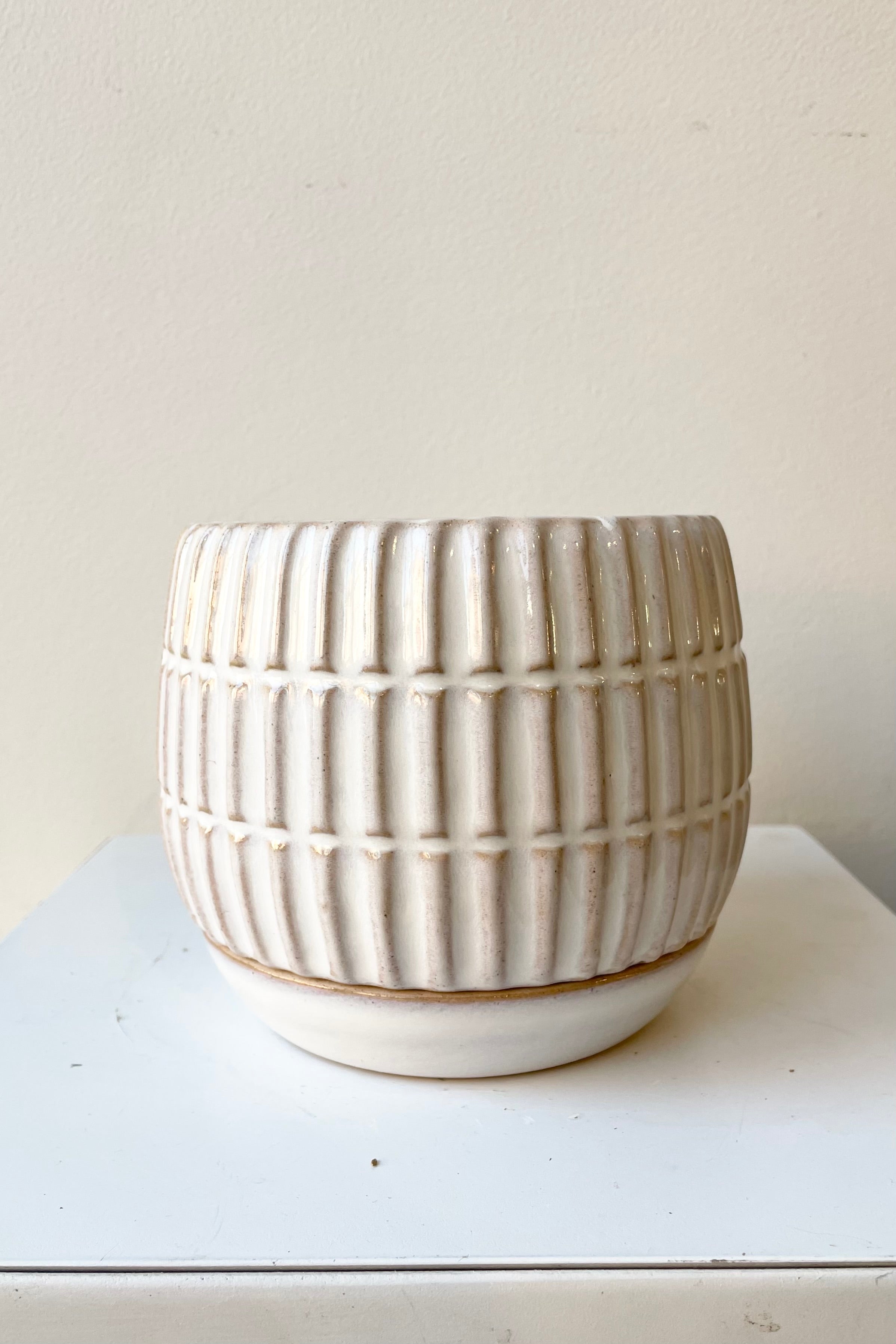 The stoneware Ramos 4" pot with drain hole and saucer against a white wall at Sprout Home.