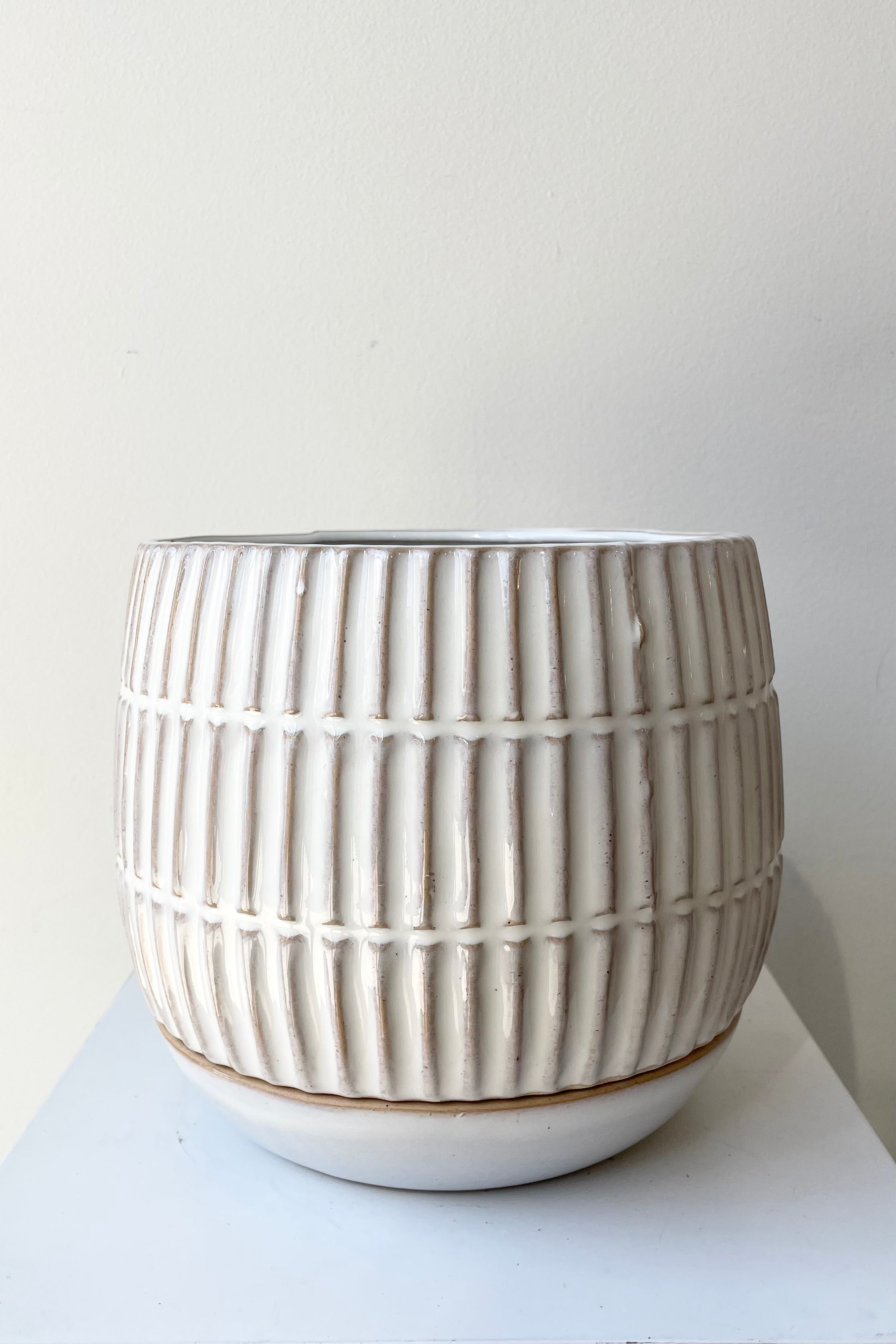 The 6" Ramos planter with saucer against a white wall at Sprout Home.