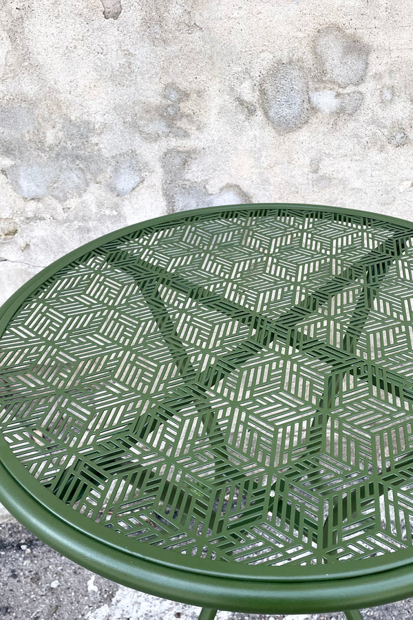 An overhead detailed view of the 23.75" Martini Iron Round Bistro Table in Moss against a concrete backdrop 