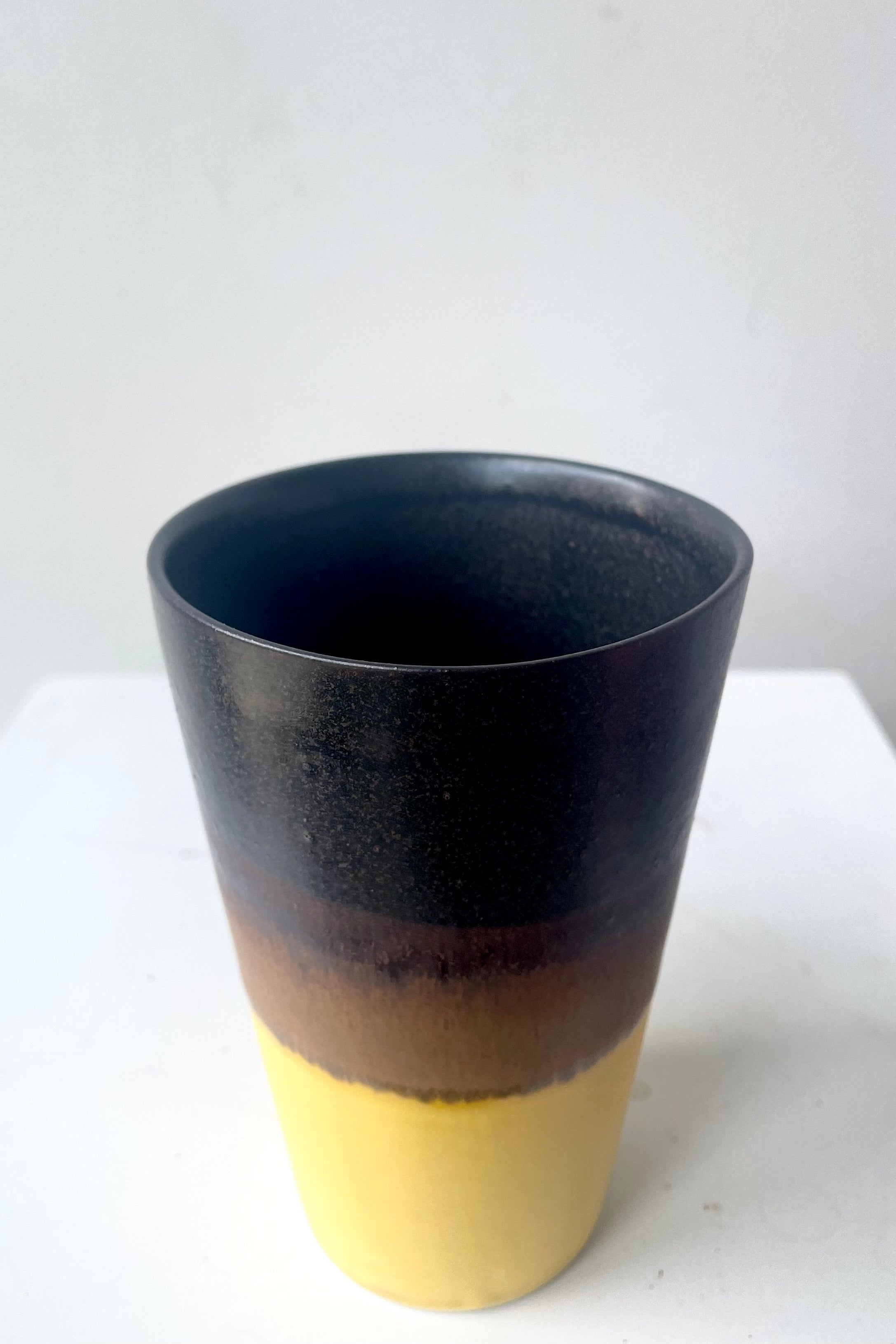 A slight overhead view of Tumbler black & golden glaze against white backdrop & golden glaze