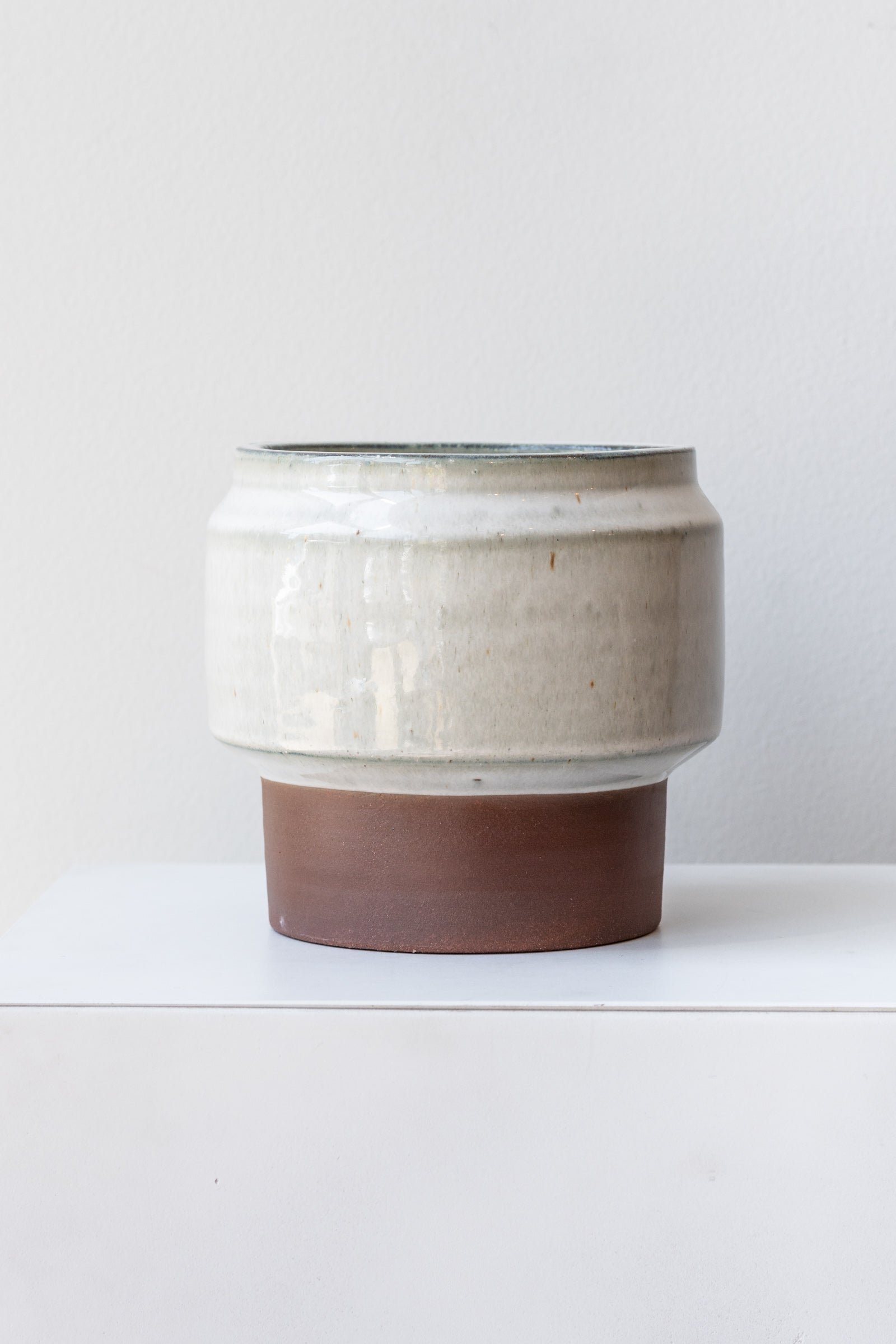 White and brown footed Alta vase by Homart on a white surface in a white room