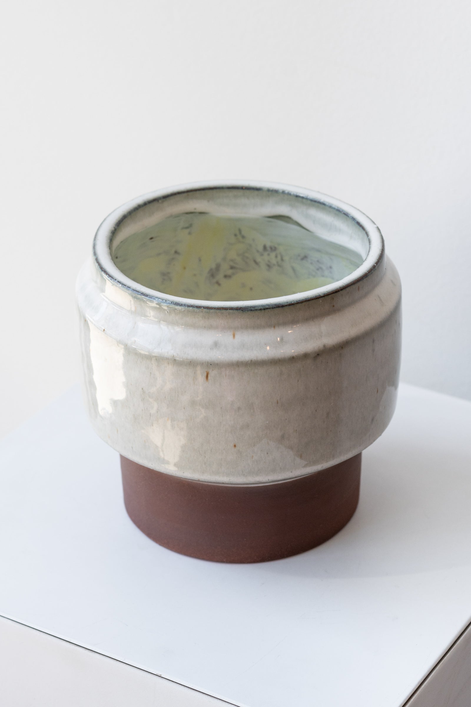 White and brown footed Alta vase by Homart on a white surface in a white room