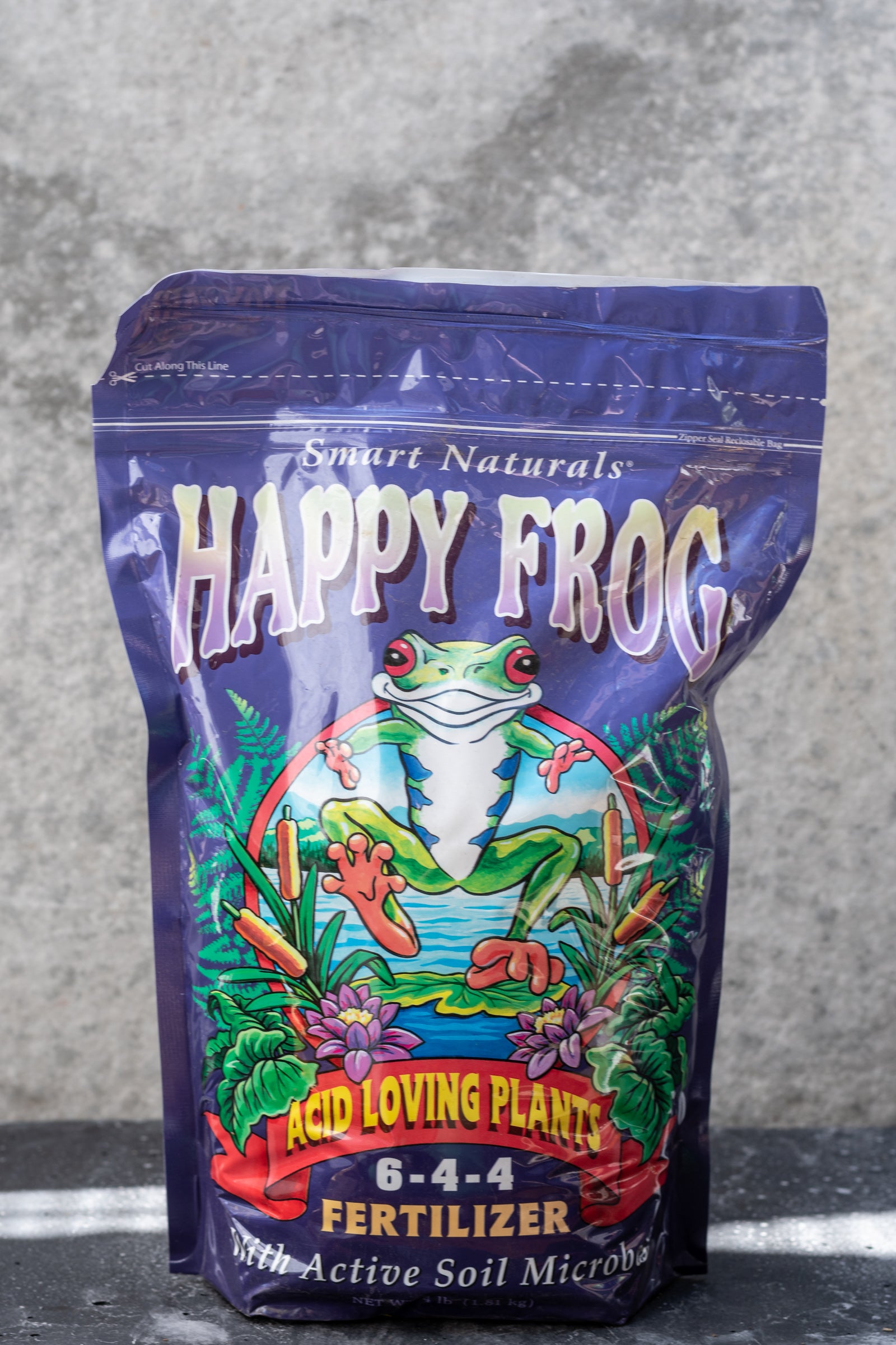 Happy Frog Fertilizer for acid loving plants in its purple bag against a grey wall. ©Sprout Home
