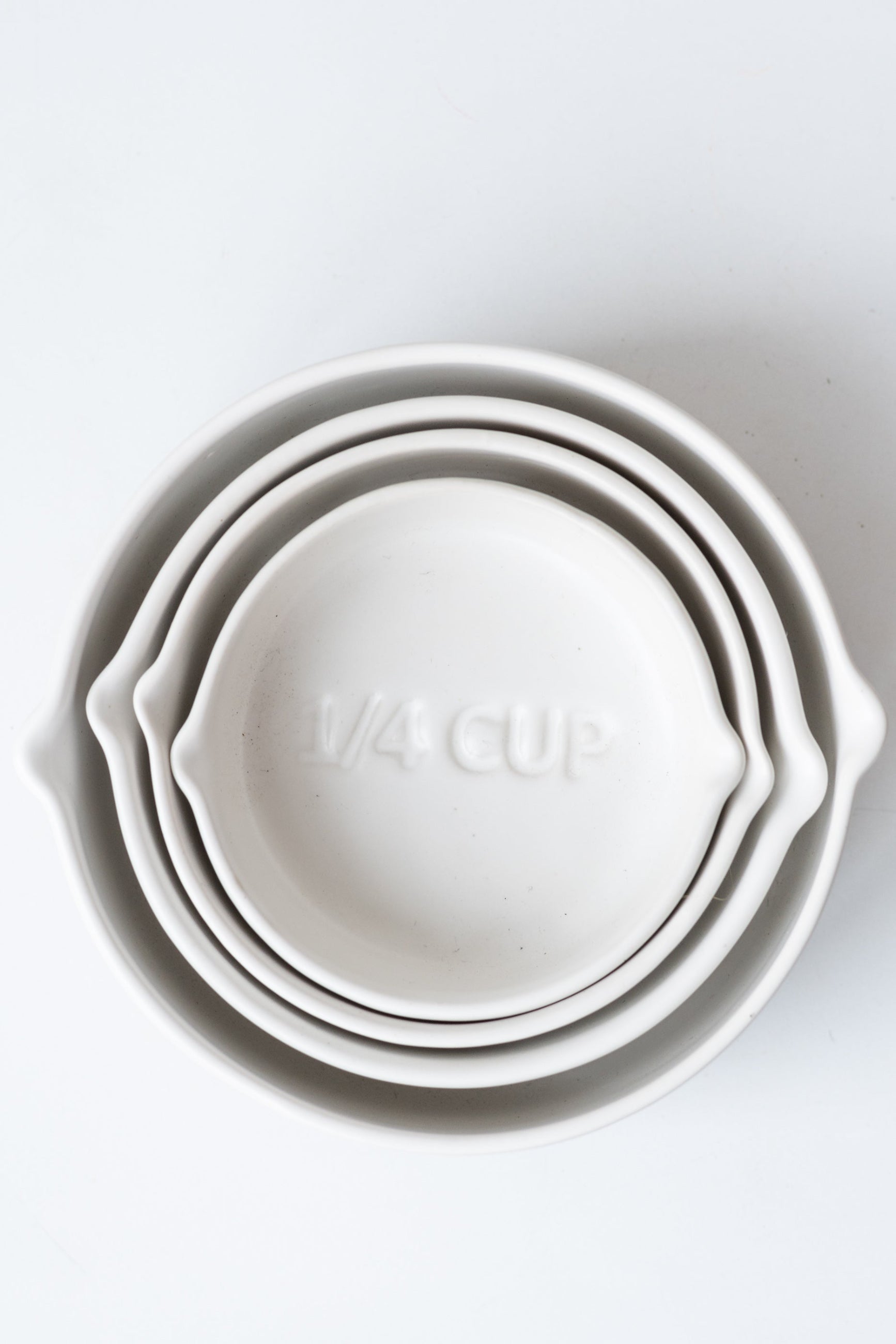White circular Stoneware Measuring Cup Set nested against a white background ©Sprout Home
