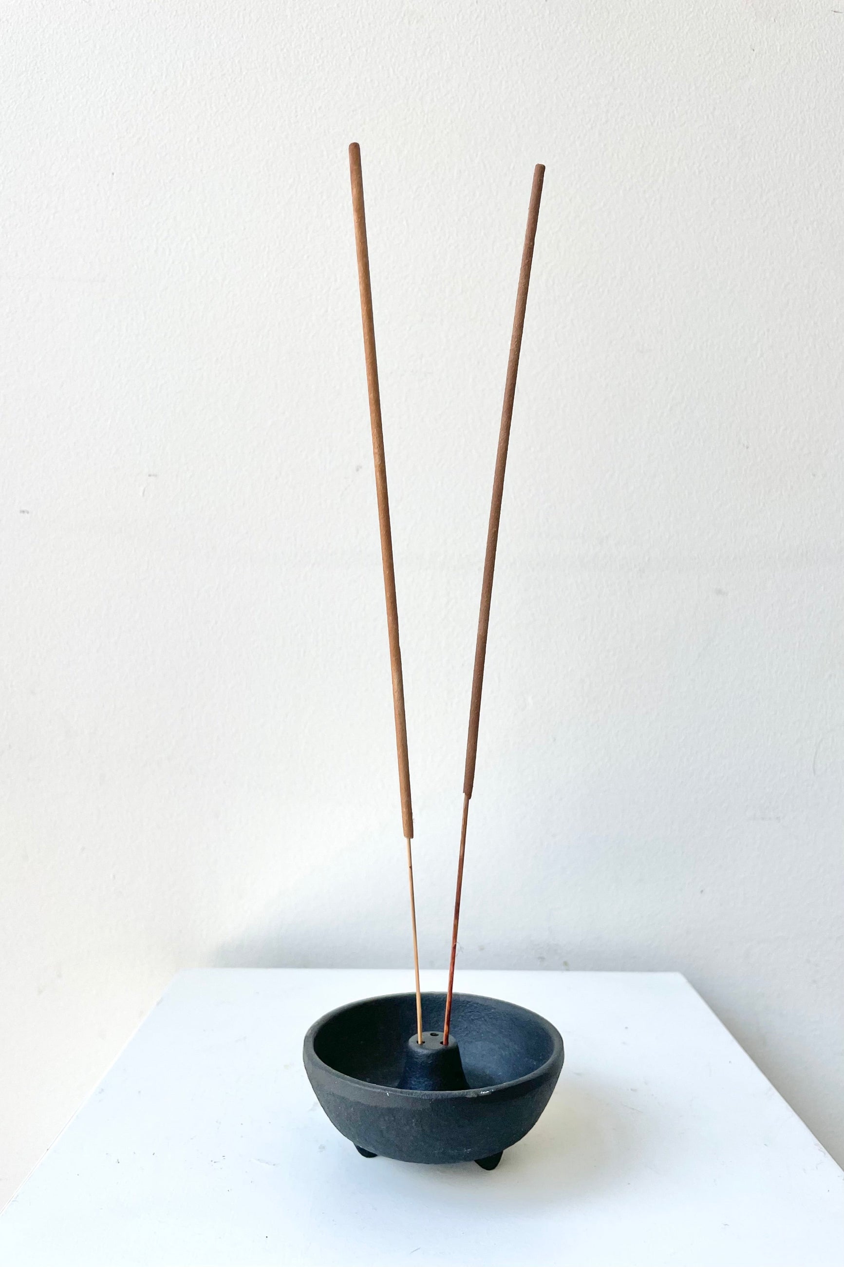 Incense Weight black with two insense sticks against a white wall ©Sprout Home
