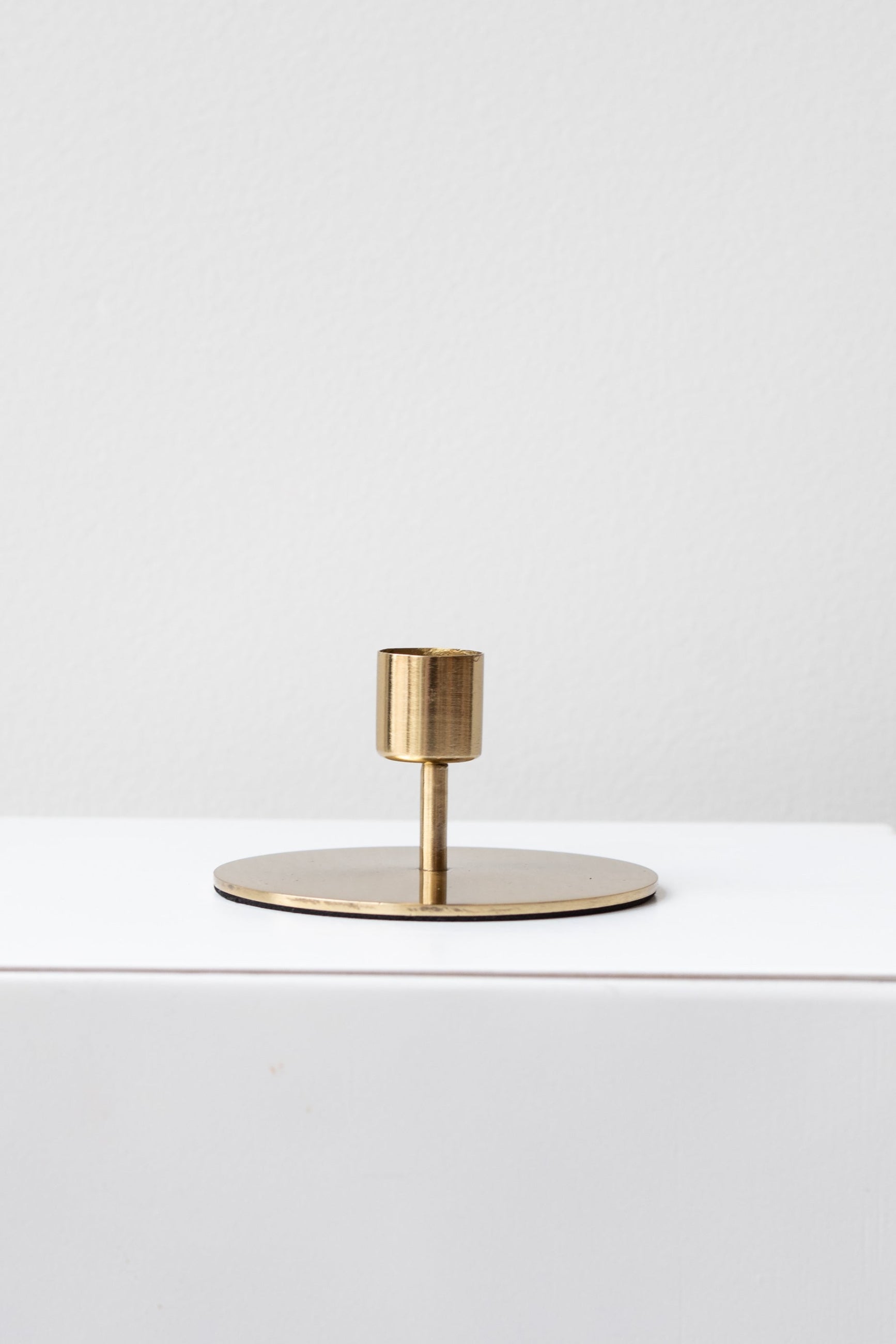 A simple, elegant gold-colored metal taper candle holder with a sleek silhouette. ©Sprout Home