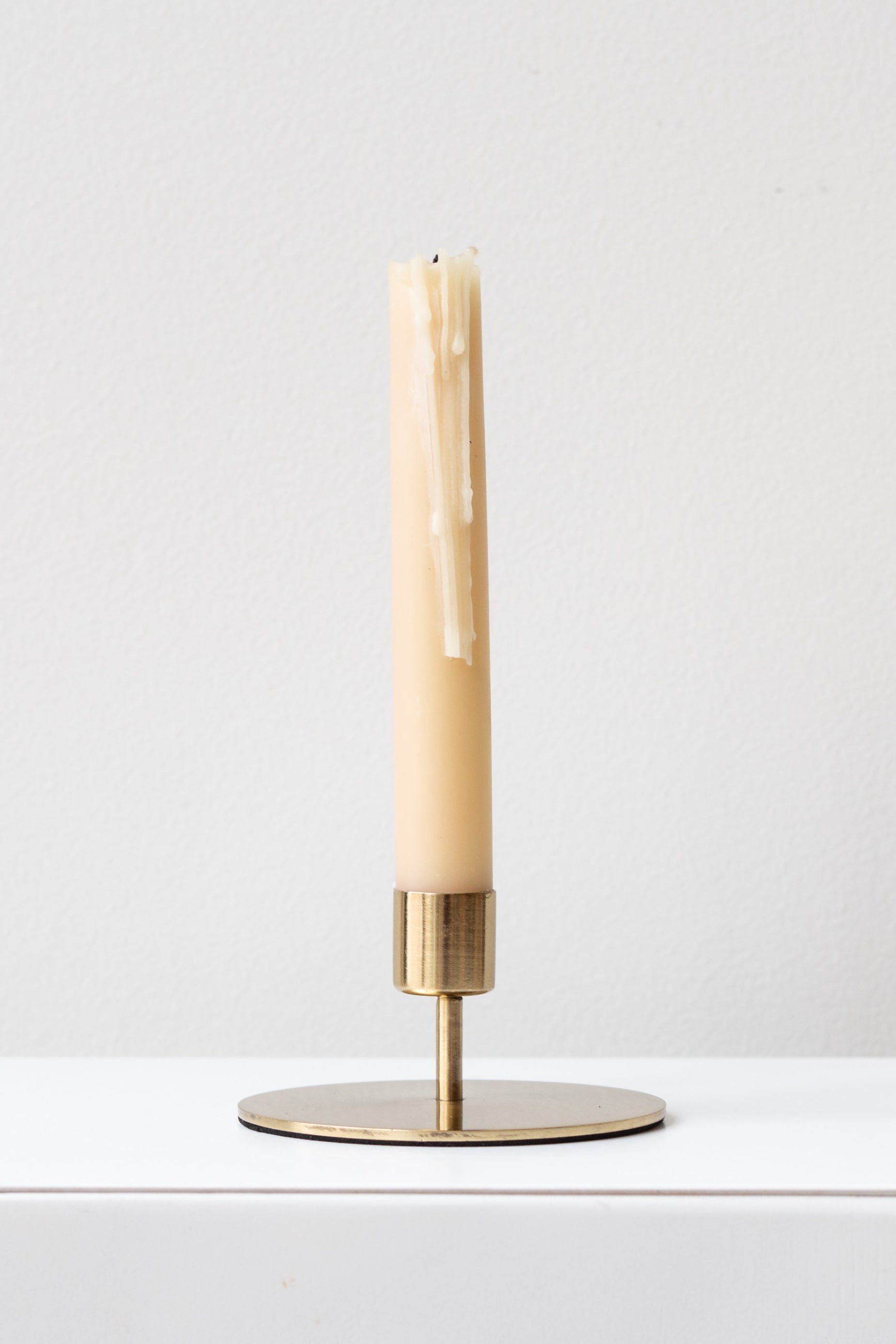 Kentt short taper gold candle holder with a neutral candle inside with slight drip marks ©Sprout Home