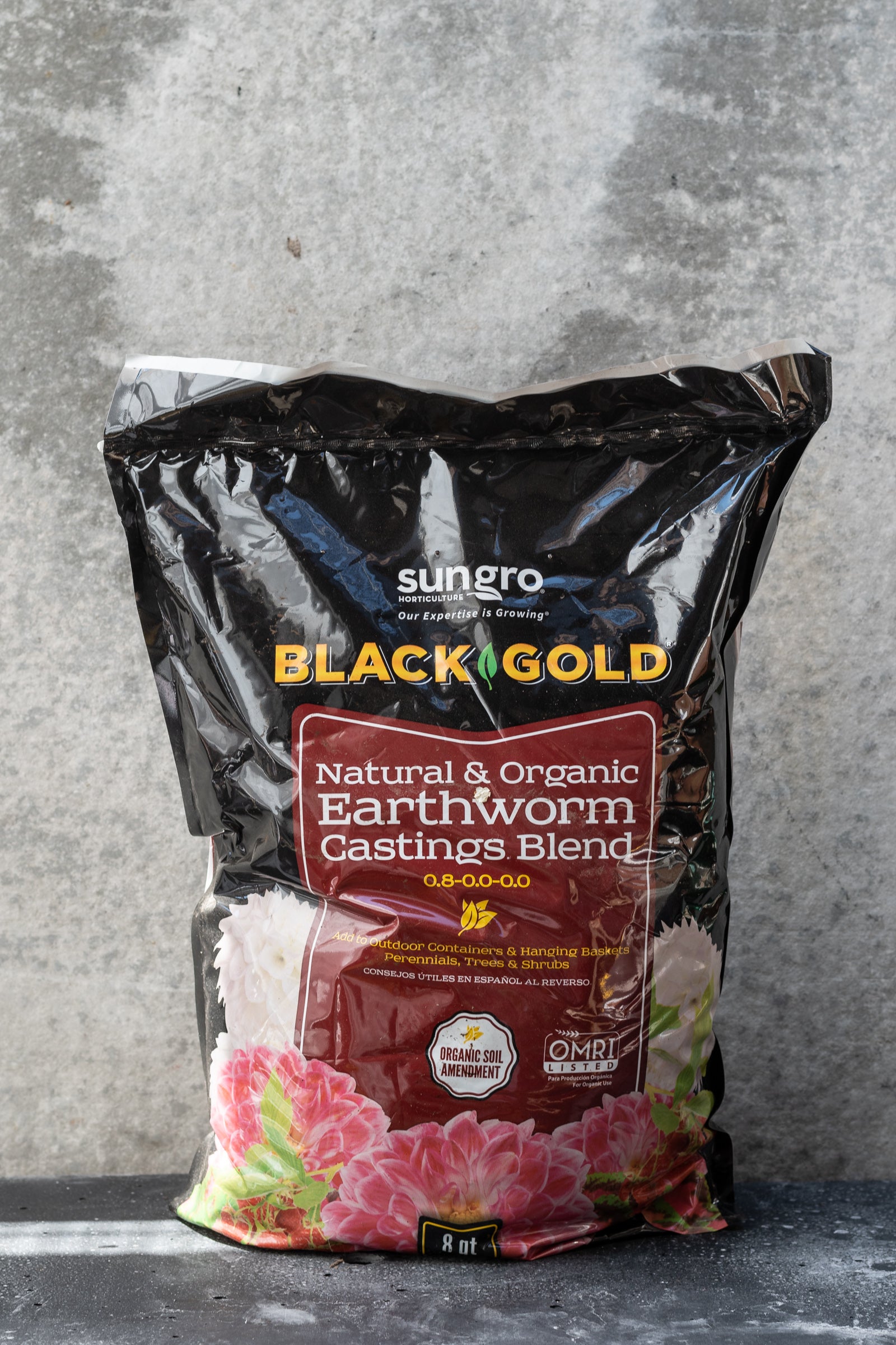 A bag of natural and organic Black Gold earthworm castings blend against a grey wall.