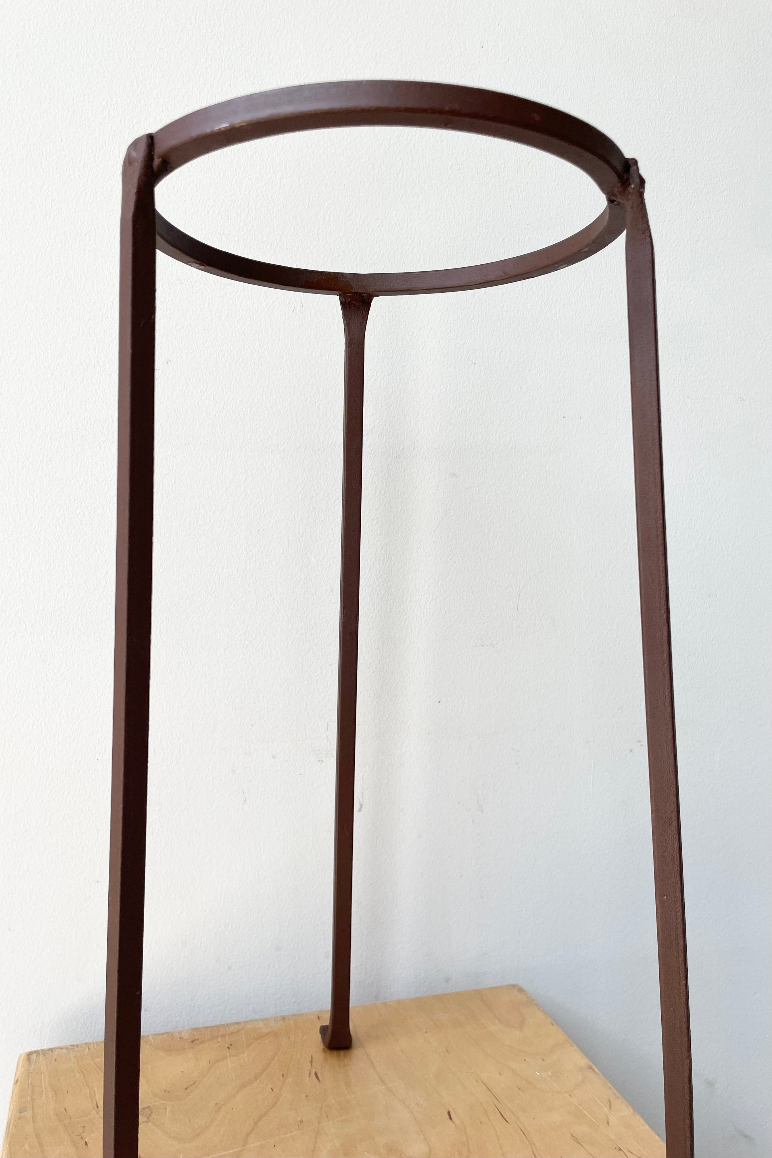 detail of the Iron Plant Stand Low 8"dia x 17"H against a white wall