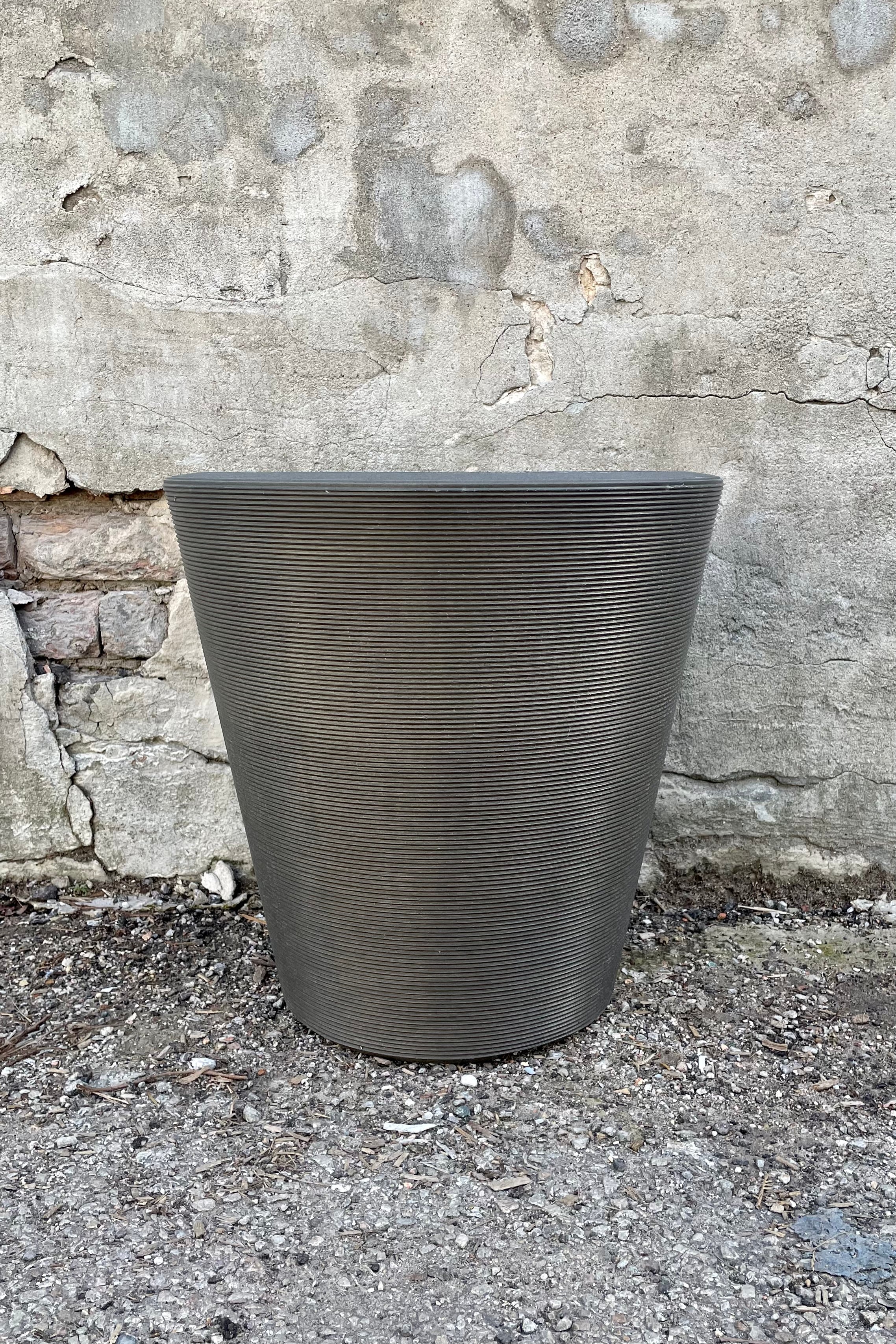 The 16" old bronze madison planter shown from the side against a concrete wall.