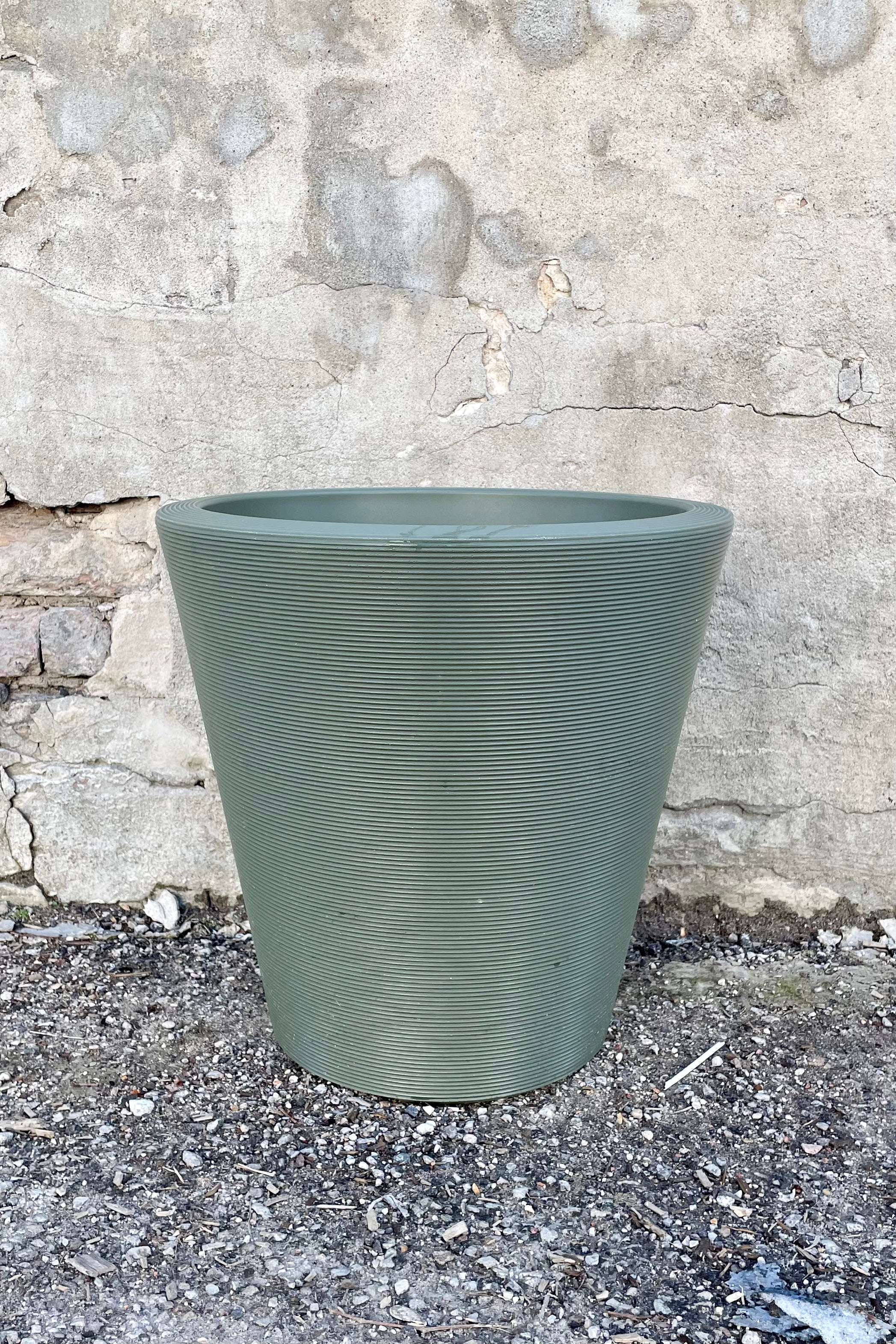 The 16" olive Madison planter against a concrete wall.