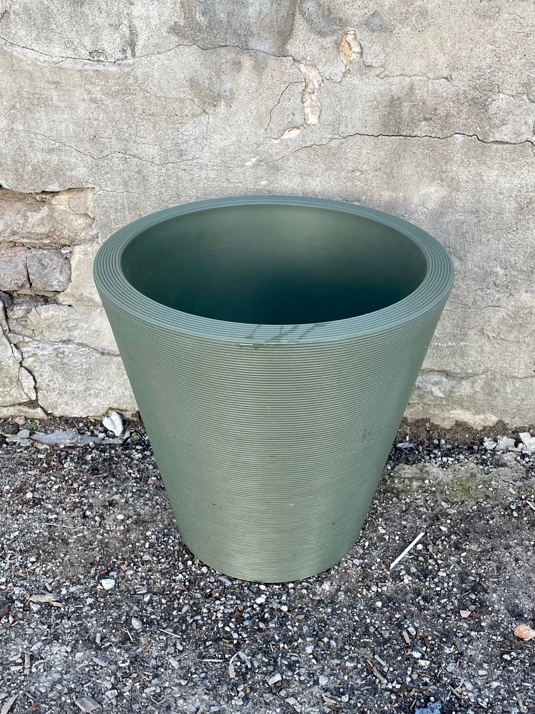 The 16" olive Madison planter against a concrete wall.