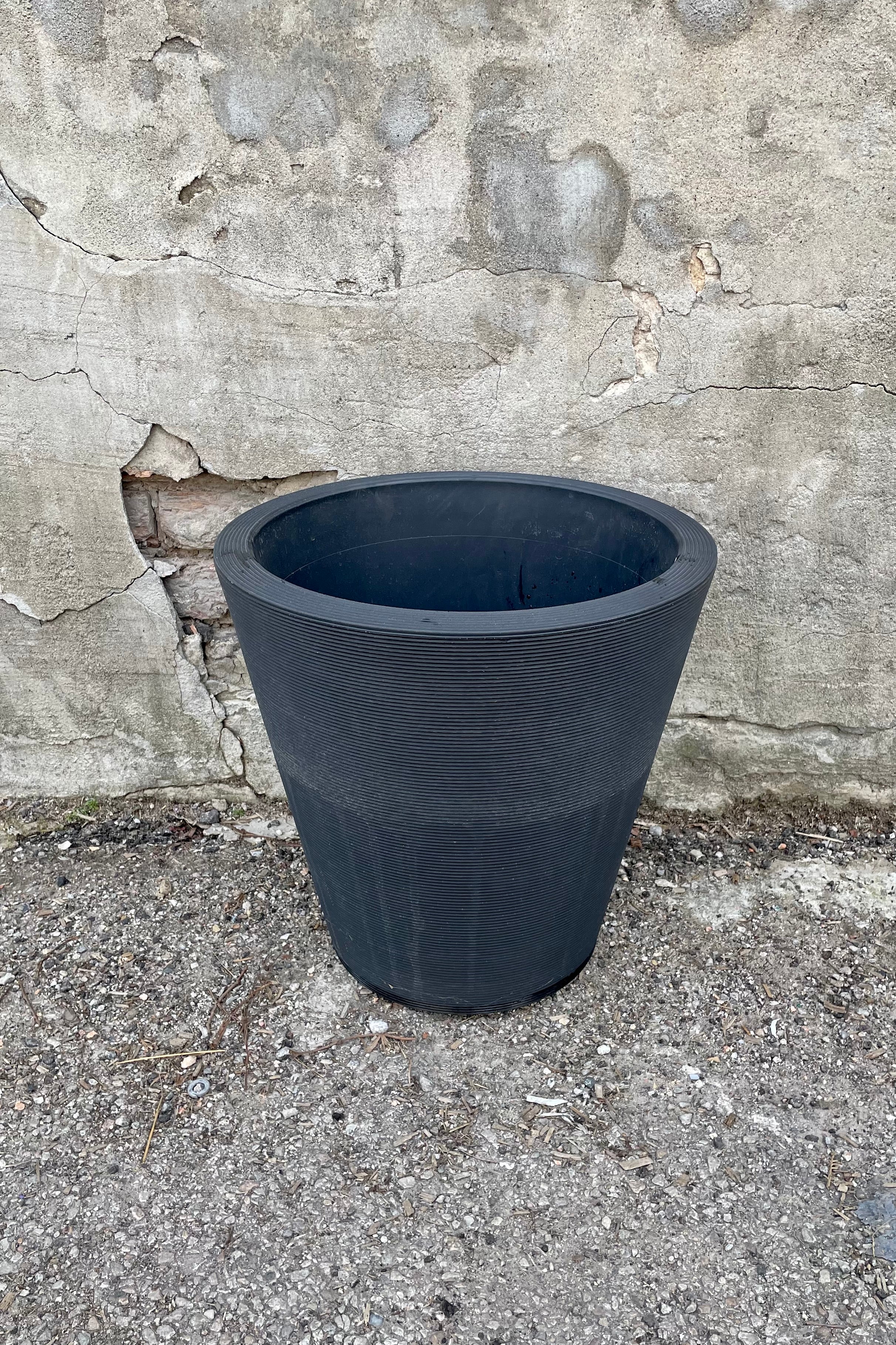 The 16" caviar black Madison pot against a concrete wall.