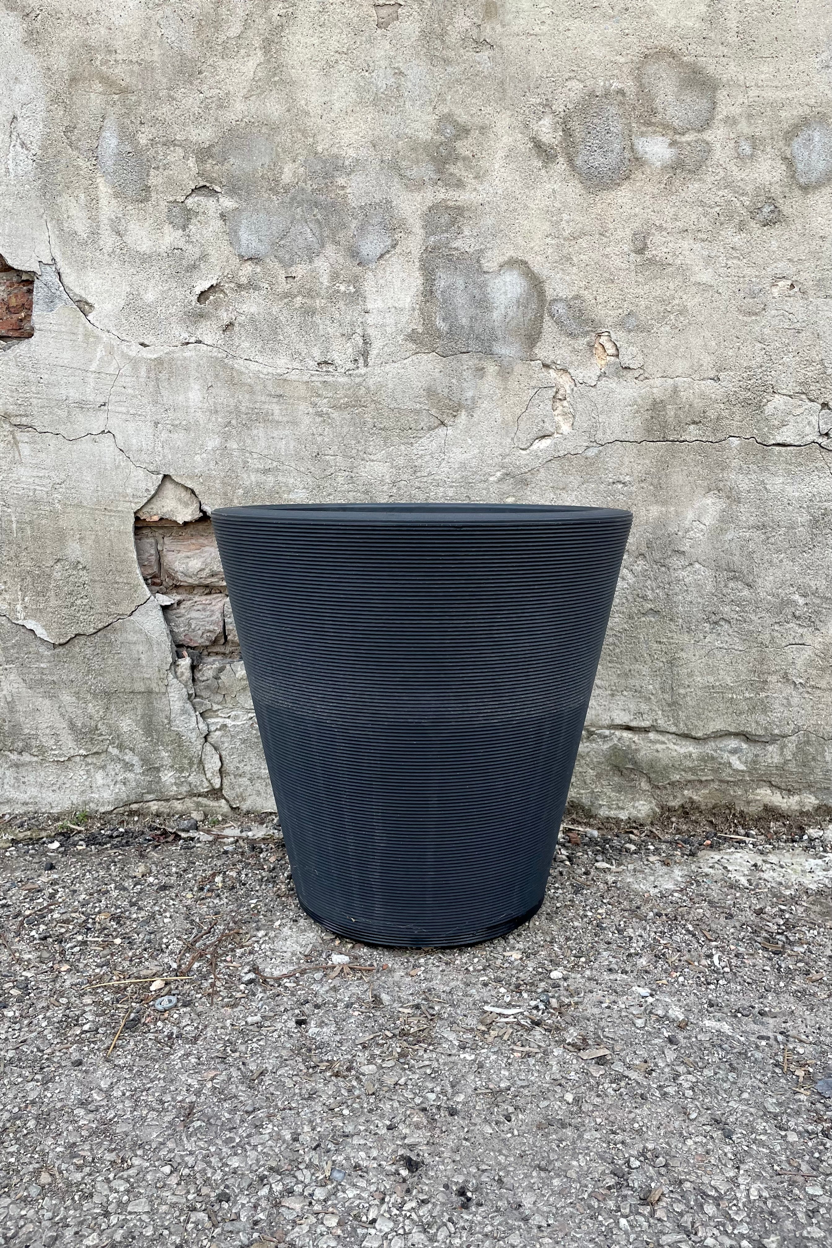The 16" caviar black Madison pot against a concrete wall.
