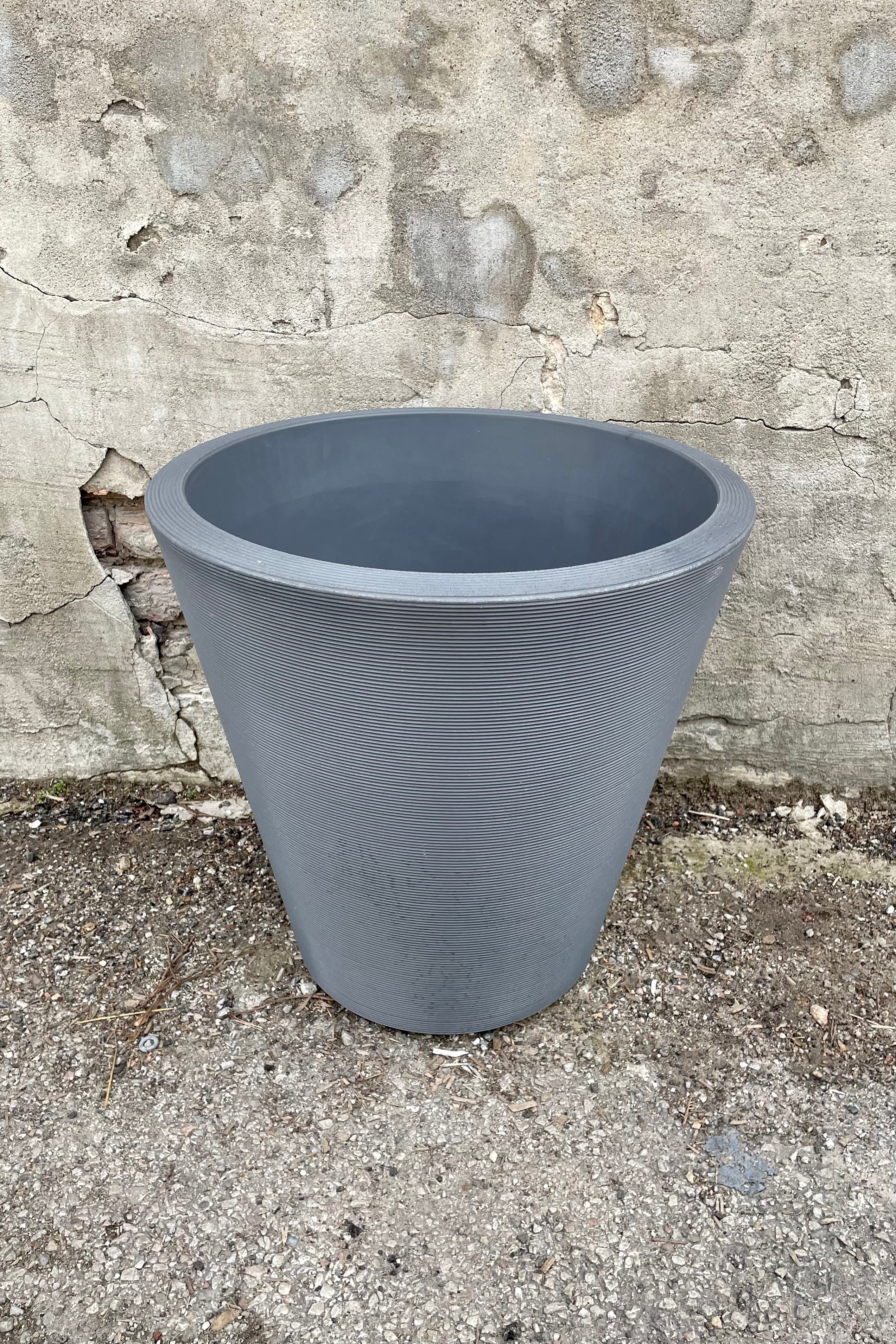 The 20" slate madison planter against a concrete wall.
