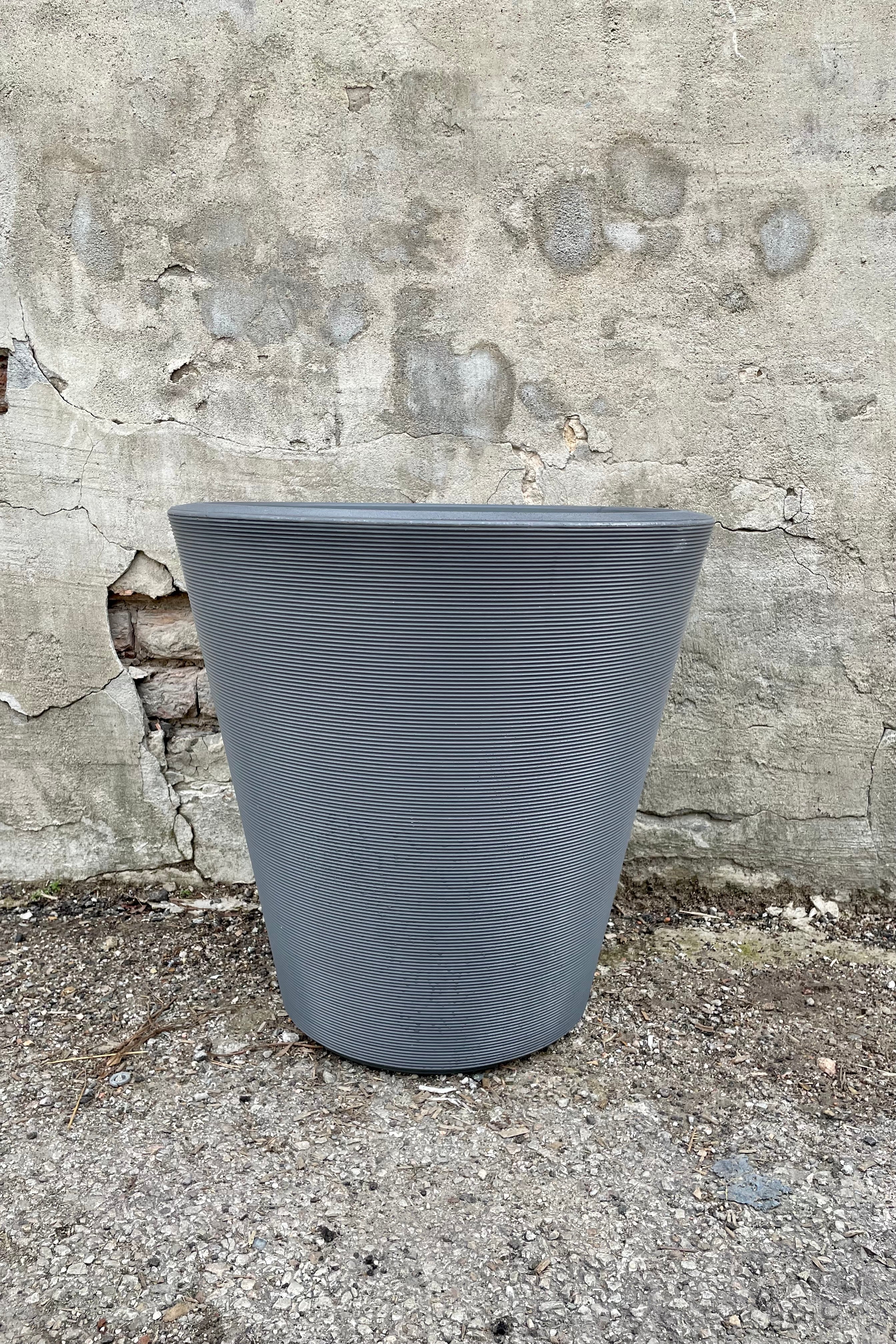 The 20" slate madison planter against a concrete wall.