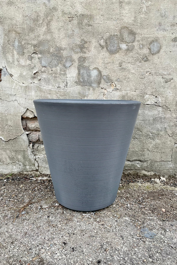 The 20" slate madison planter against a concrete wall. 