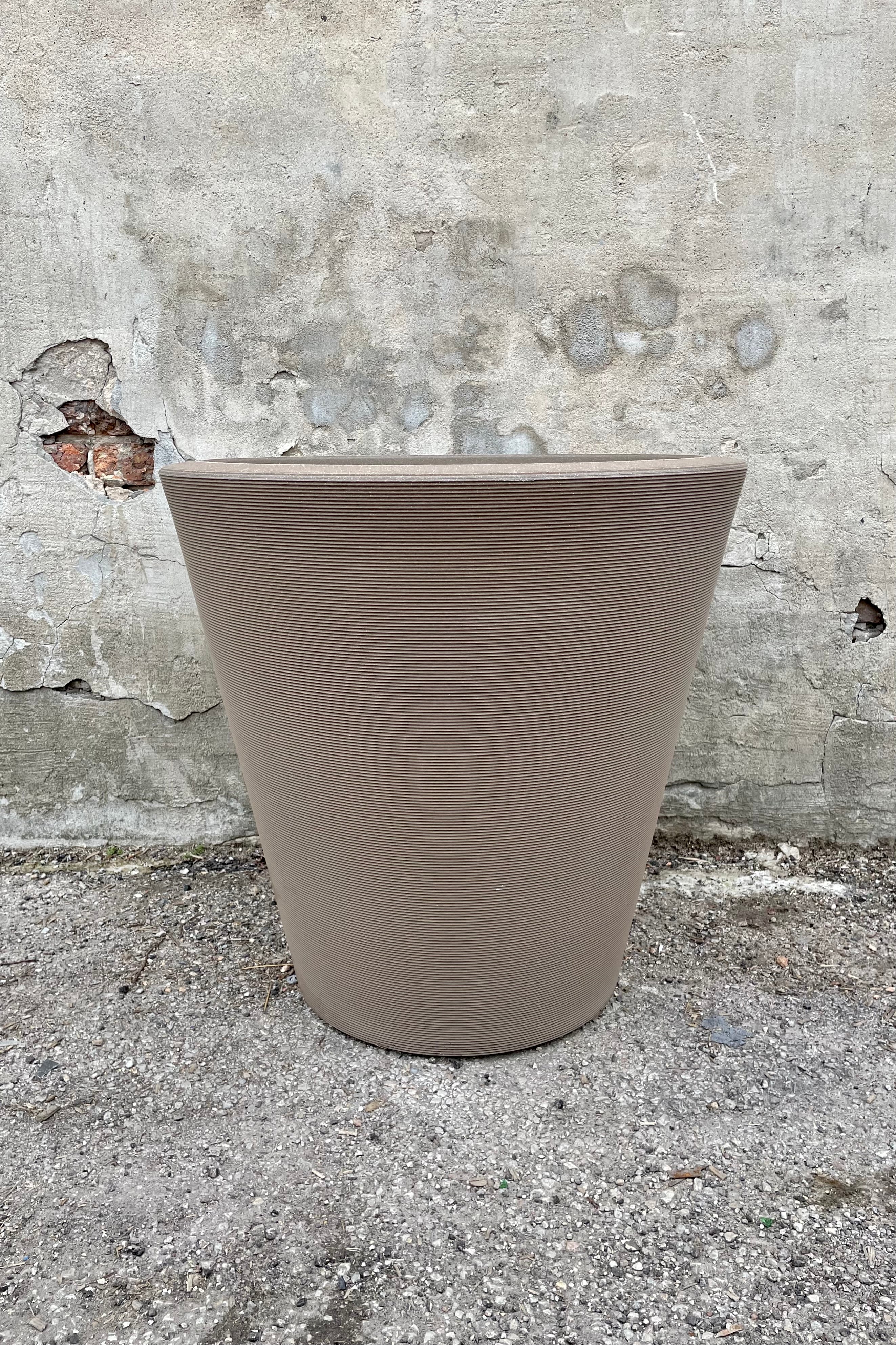 The 26" mocha Madison planter shown from the front against against a concrete wall.