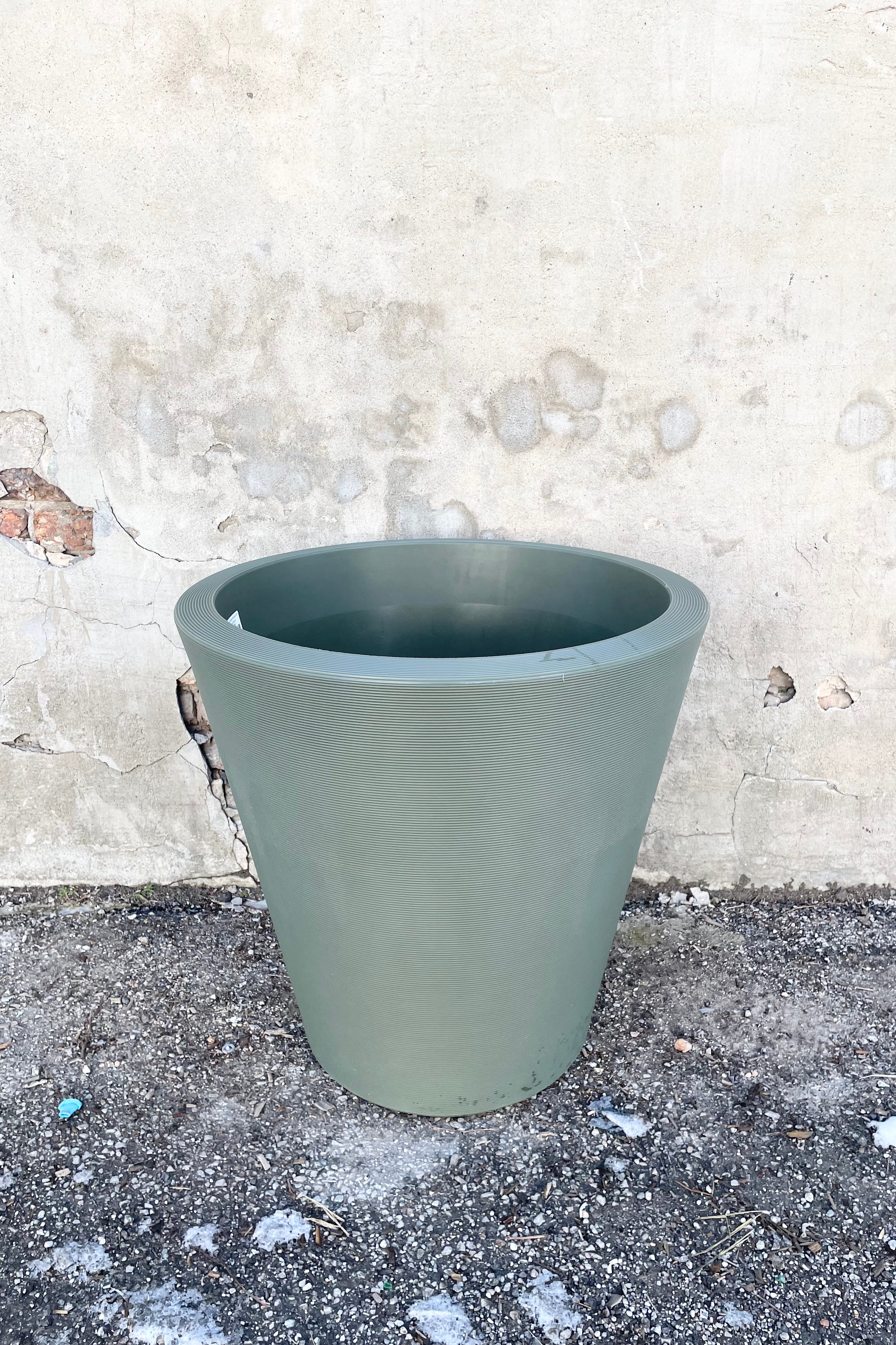 The olive 26" Madison planter against a concrete wall.